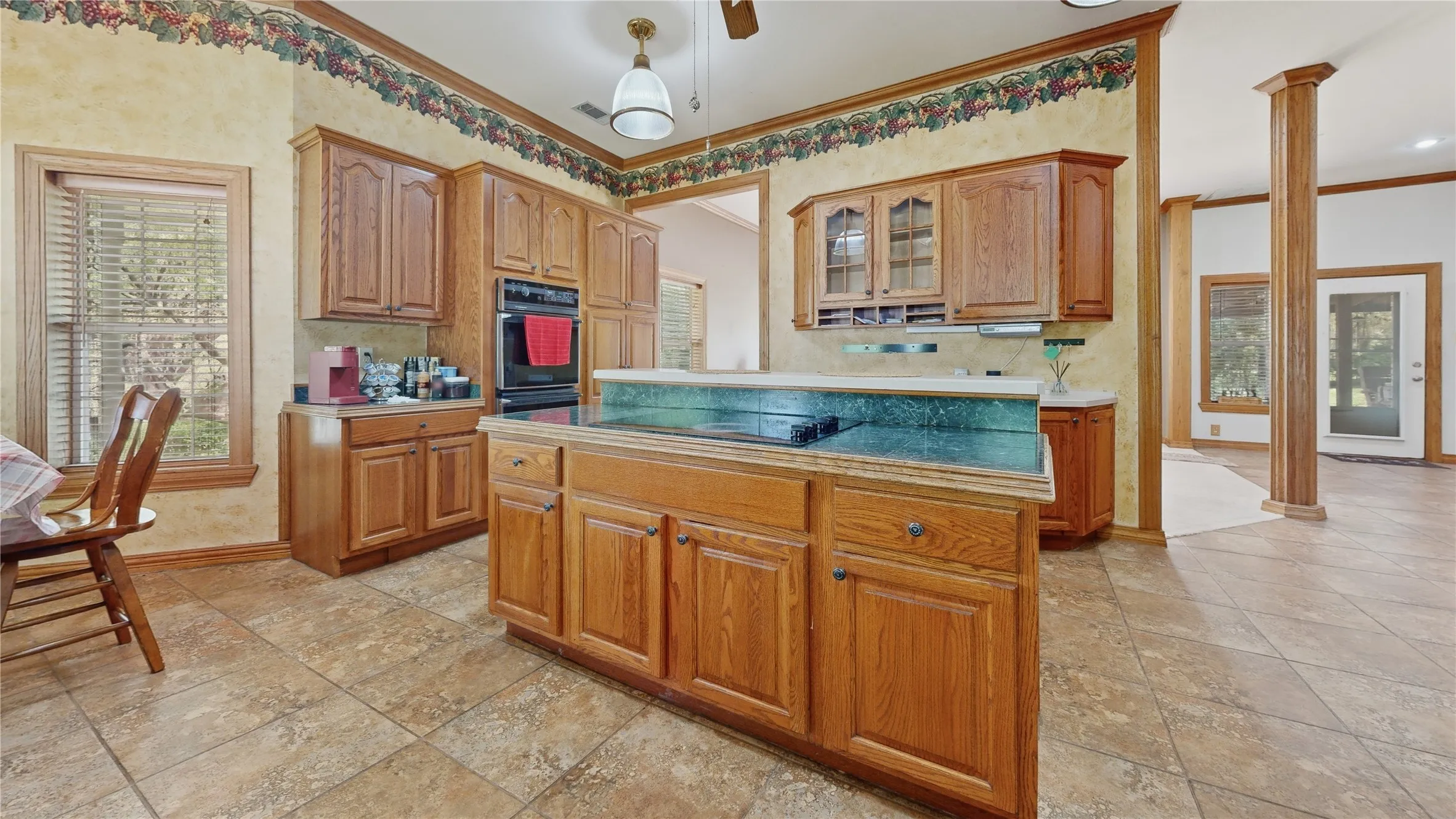 Kitchen featuring wood-finish cabinetry, a built-in oven, a center island with a cooktop, and tile flooring