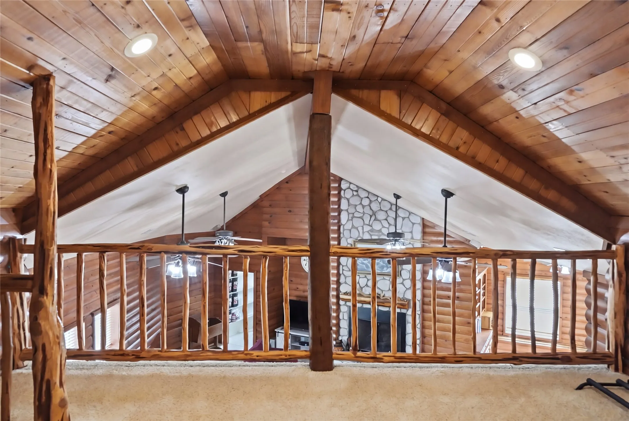 Loft area featuring a wooden railing and wood-paneled ceiling with recessed lighting