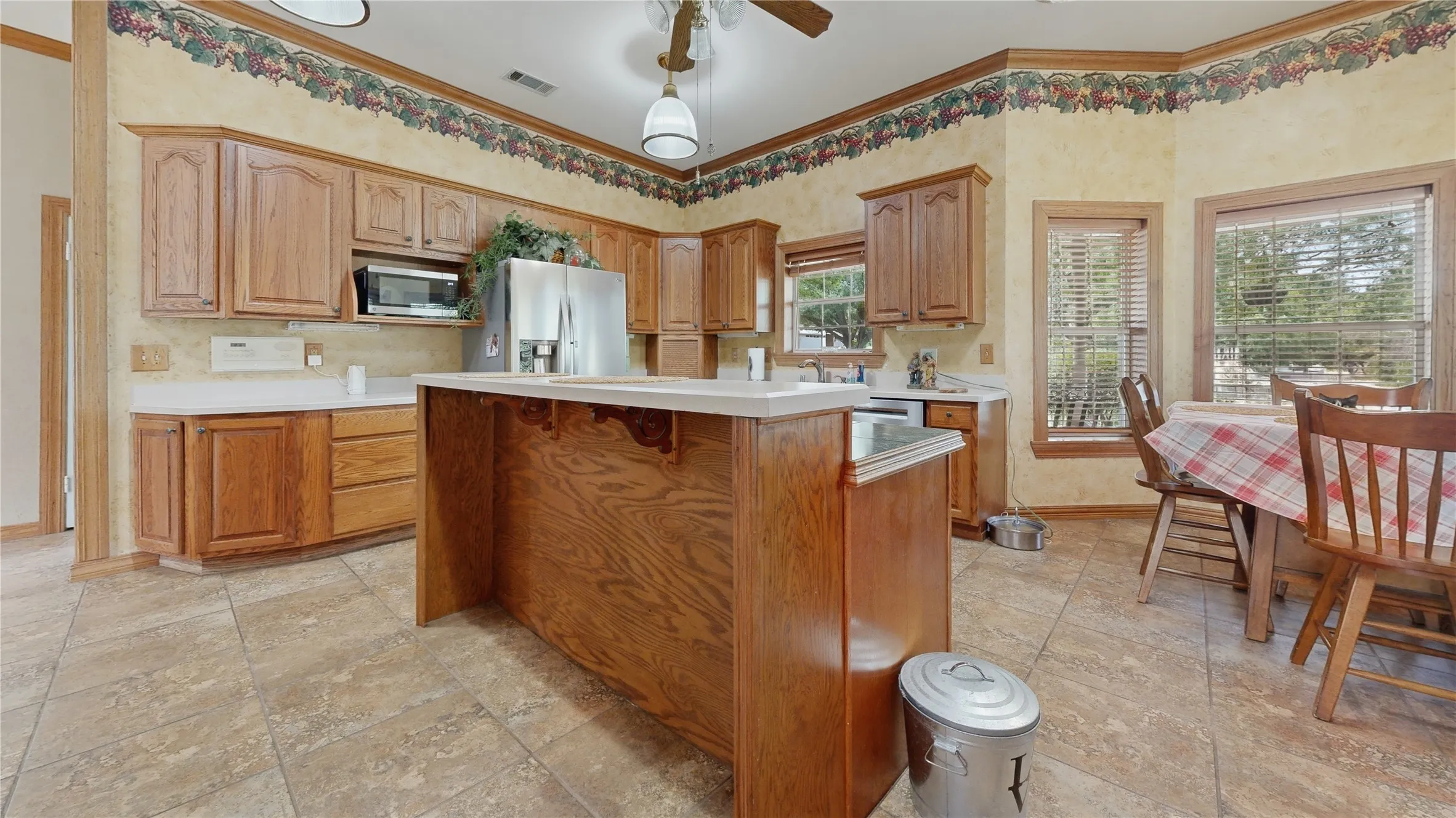Kitchen featuring wood cabinetry, white countertops, a central island, tile flooring, and integrated stainless steel appliances