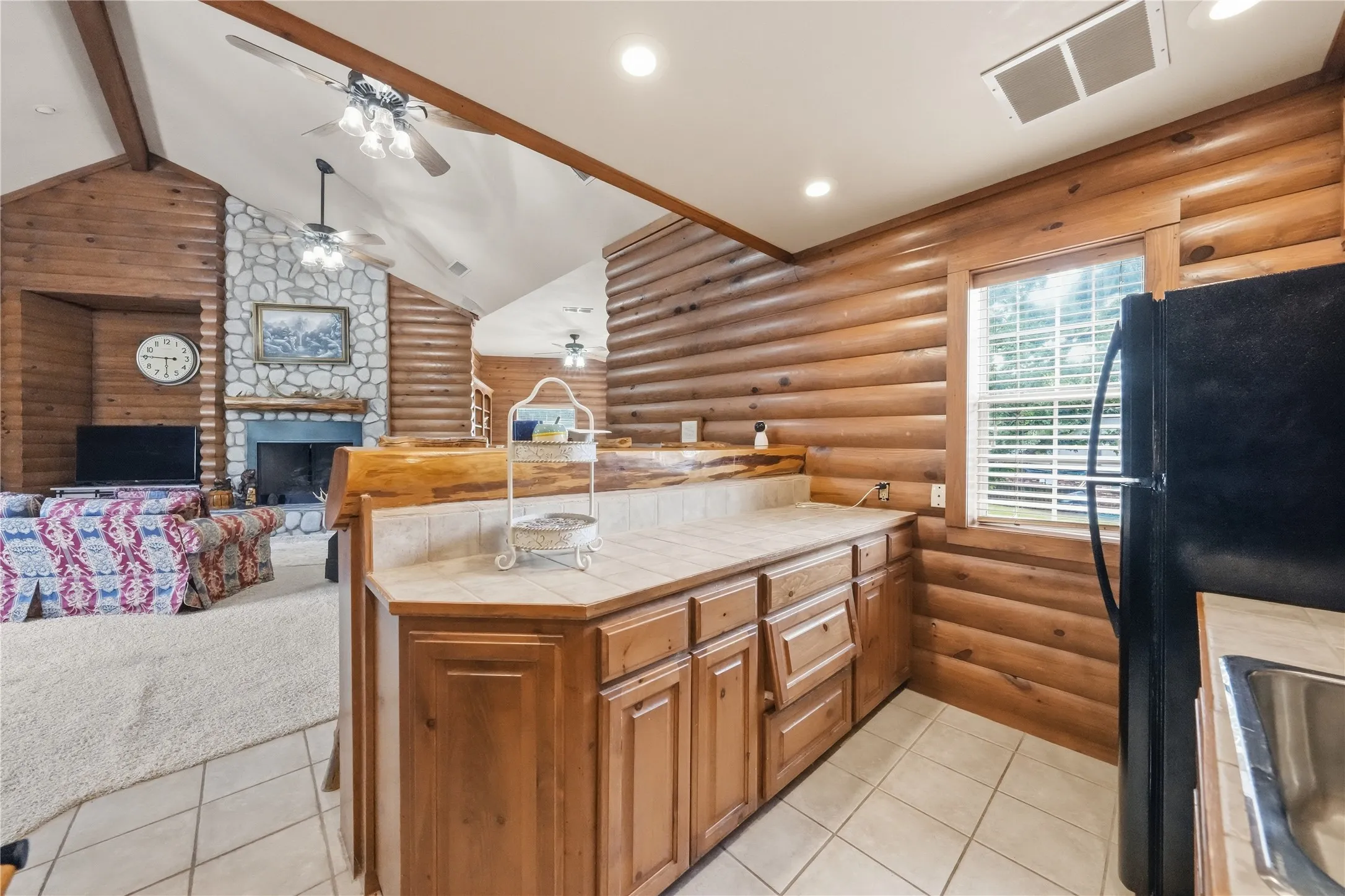 Kitchen area featuring wood-finish cabinetry, tile countertops, and a stainless steel sink