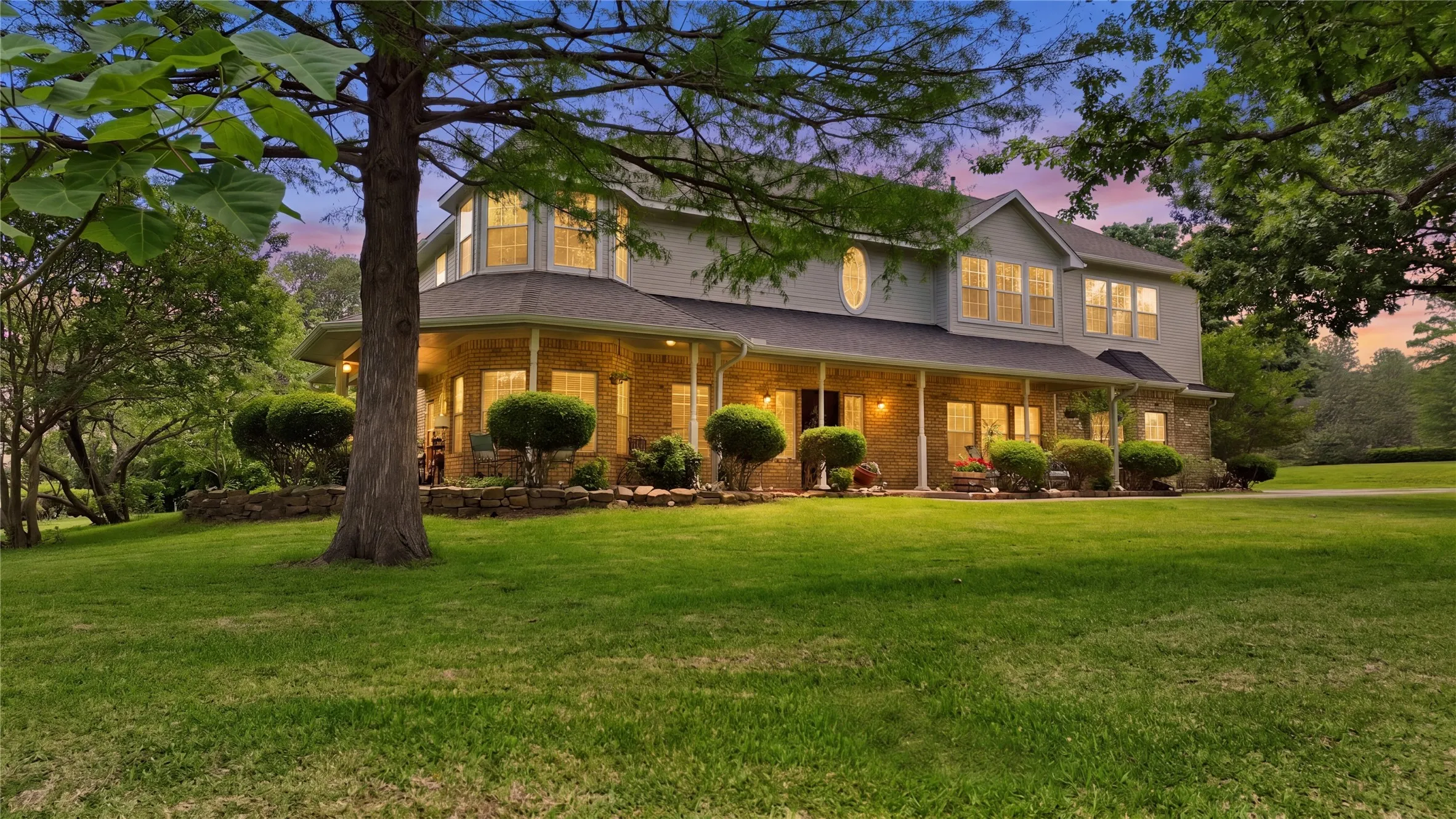 Two-story residence featuring a full-length covered porch with stone columns