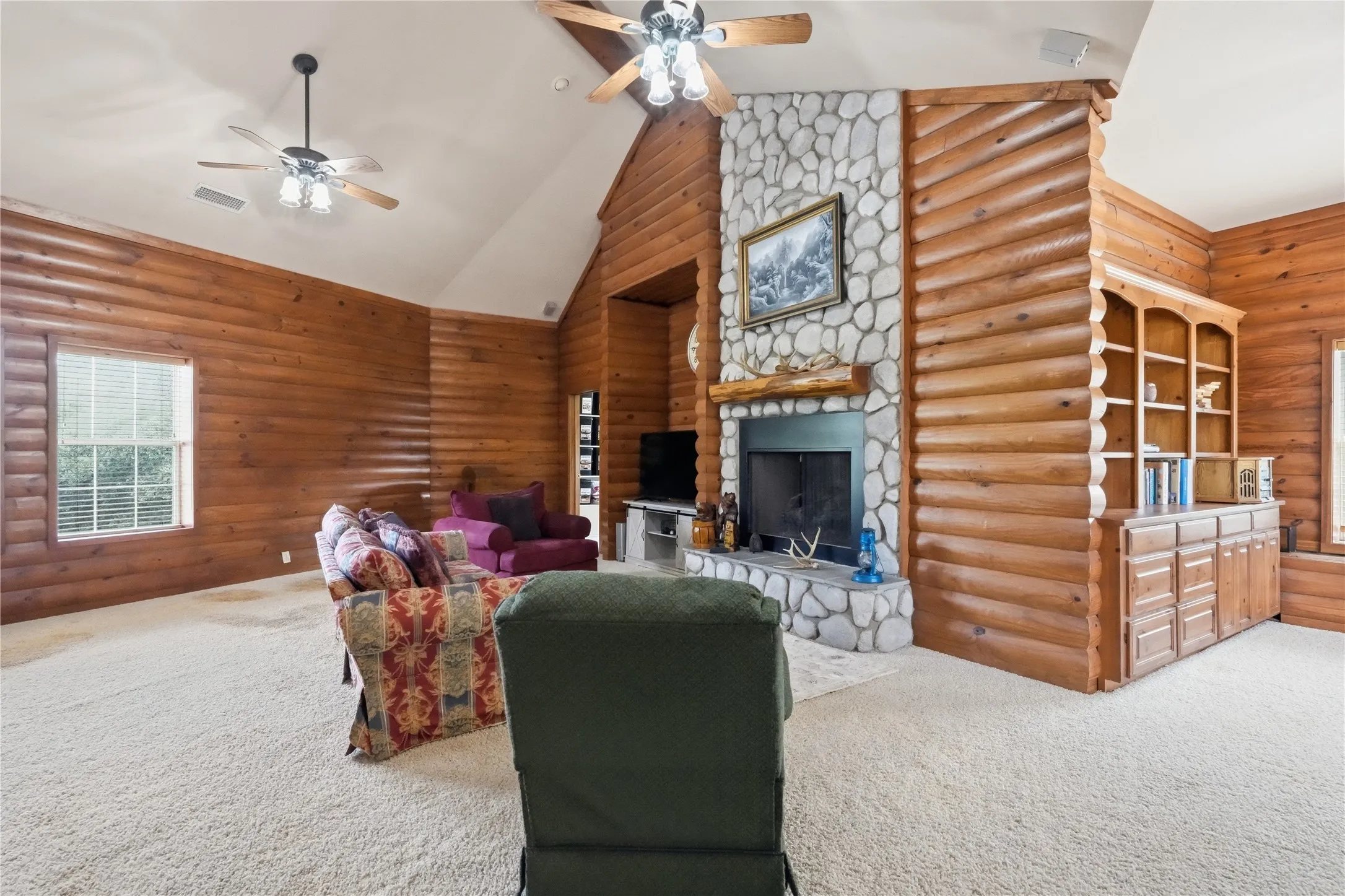 Expansive living area featuring log-style wood paneling and vaulted ceilings