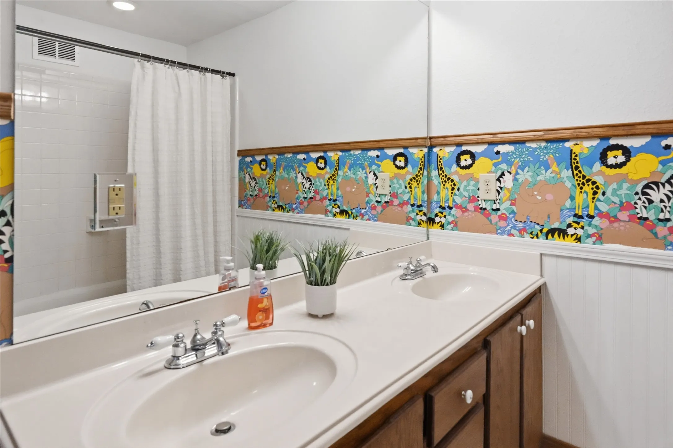 Bathroom with a dual vanity featuring integrated sinks, chrome faucets, and wood-finish cabinetry