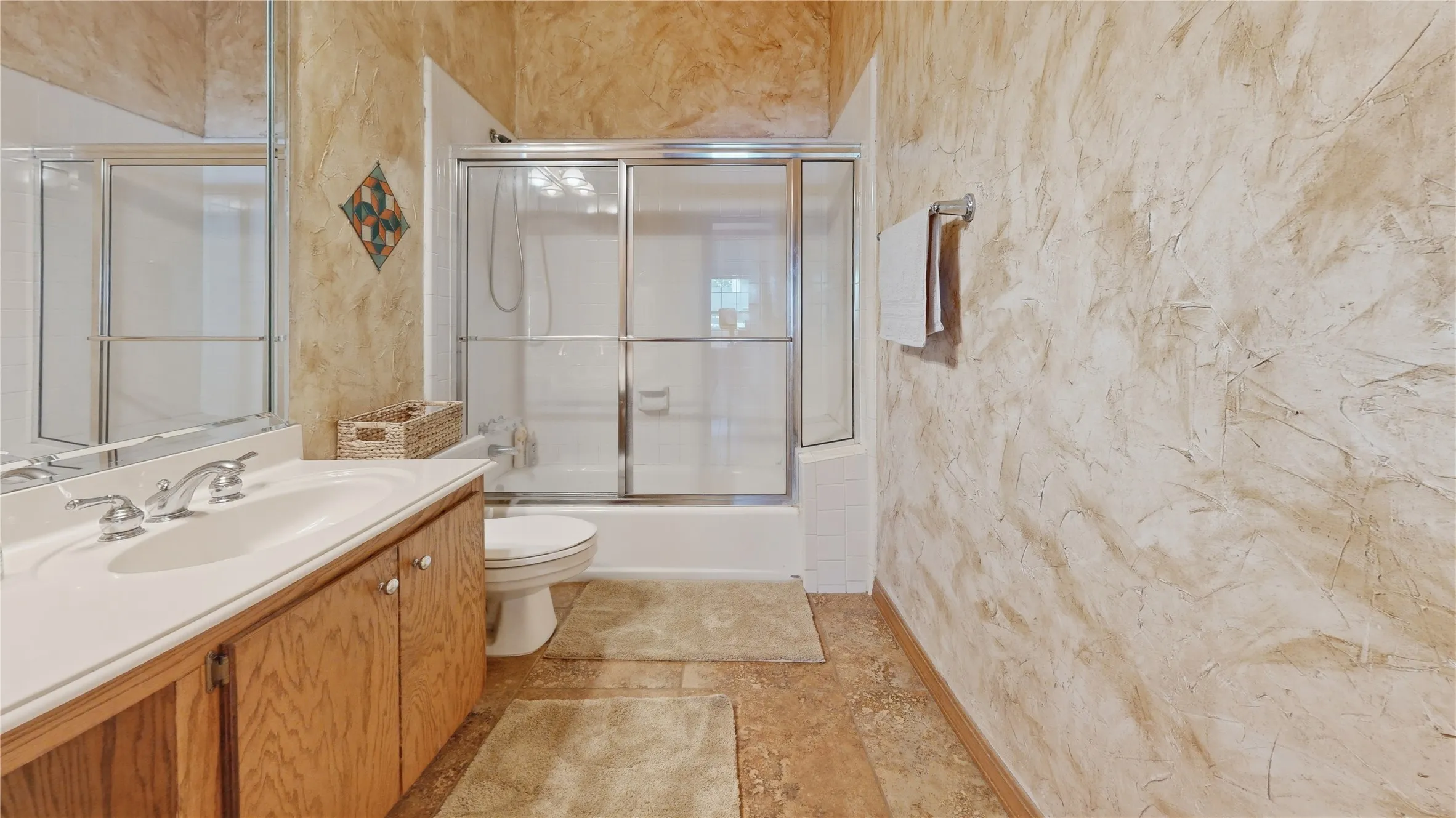 Bathroom featuring a single vanity with wood-finish cabinetry, a white countertop, and a built-in sink