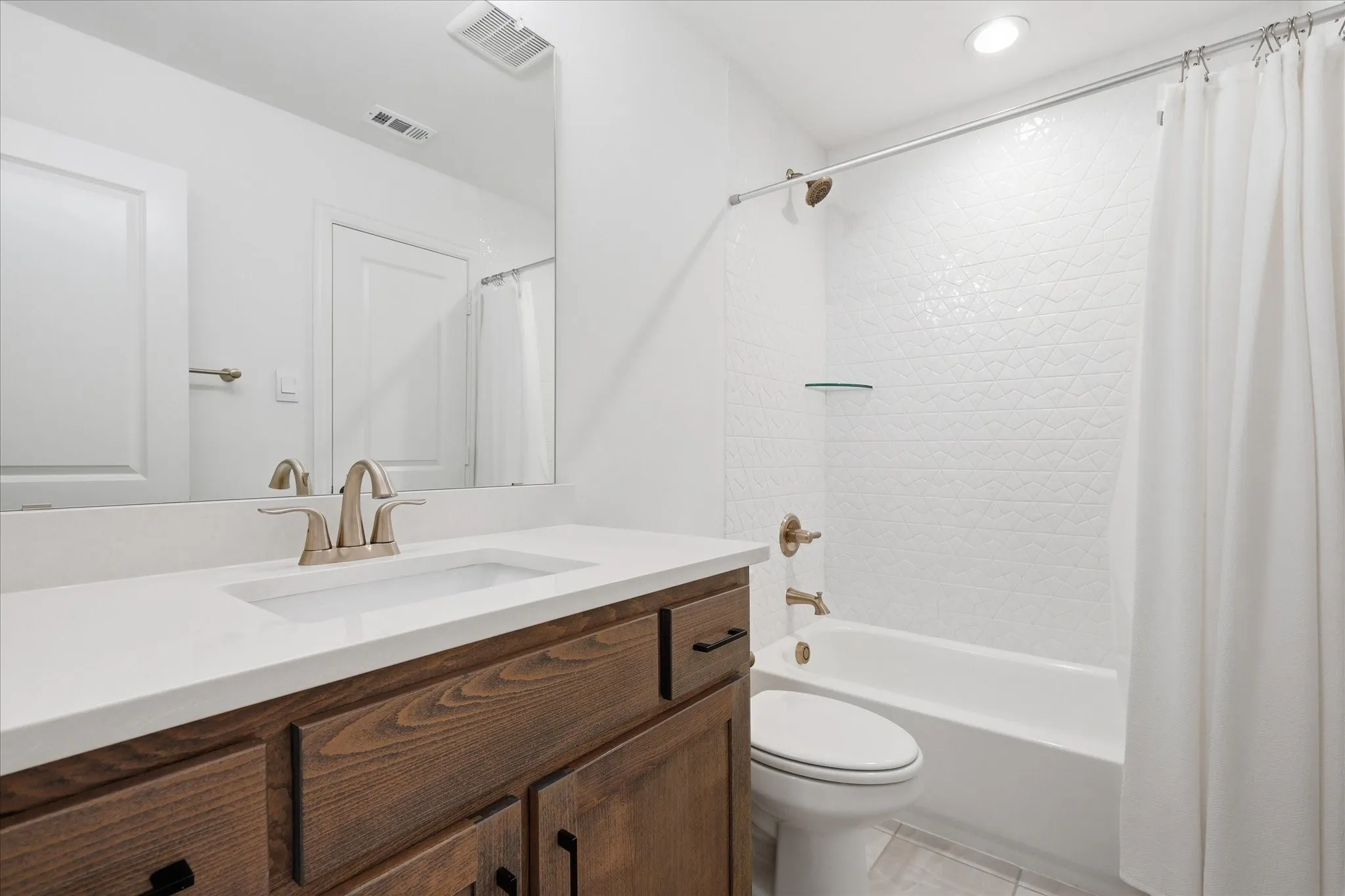 Bathroom featuring a wood-finish vanity with a white countertop and integrated sink, brushed nickel faucet, and a large mirror