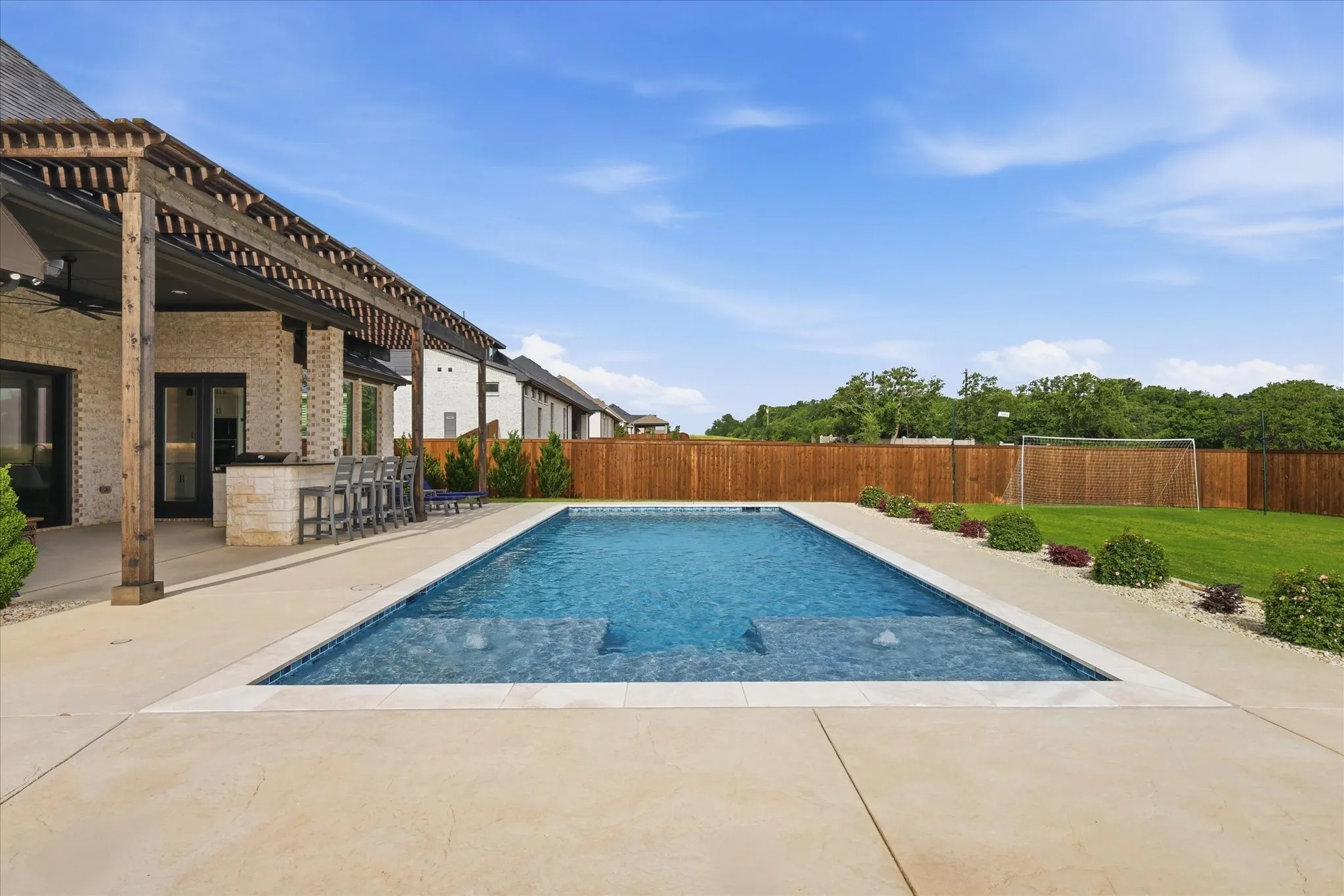 Rectangular in-ground swimming pool with integrated steps, surrounded by a light-toned concrete patio
