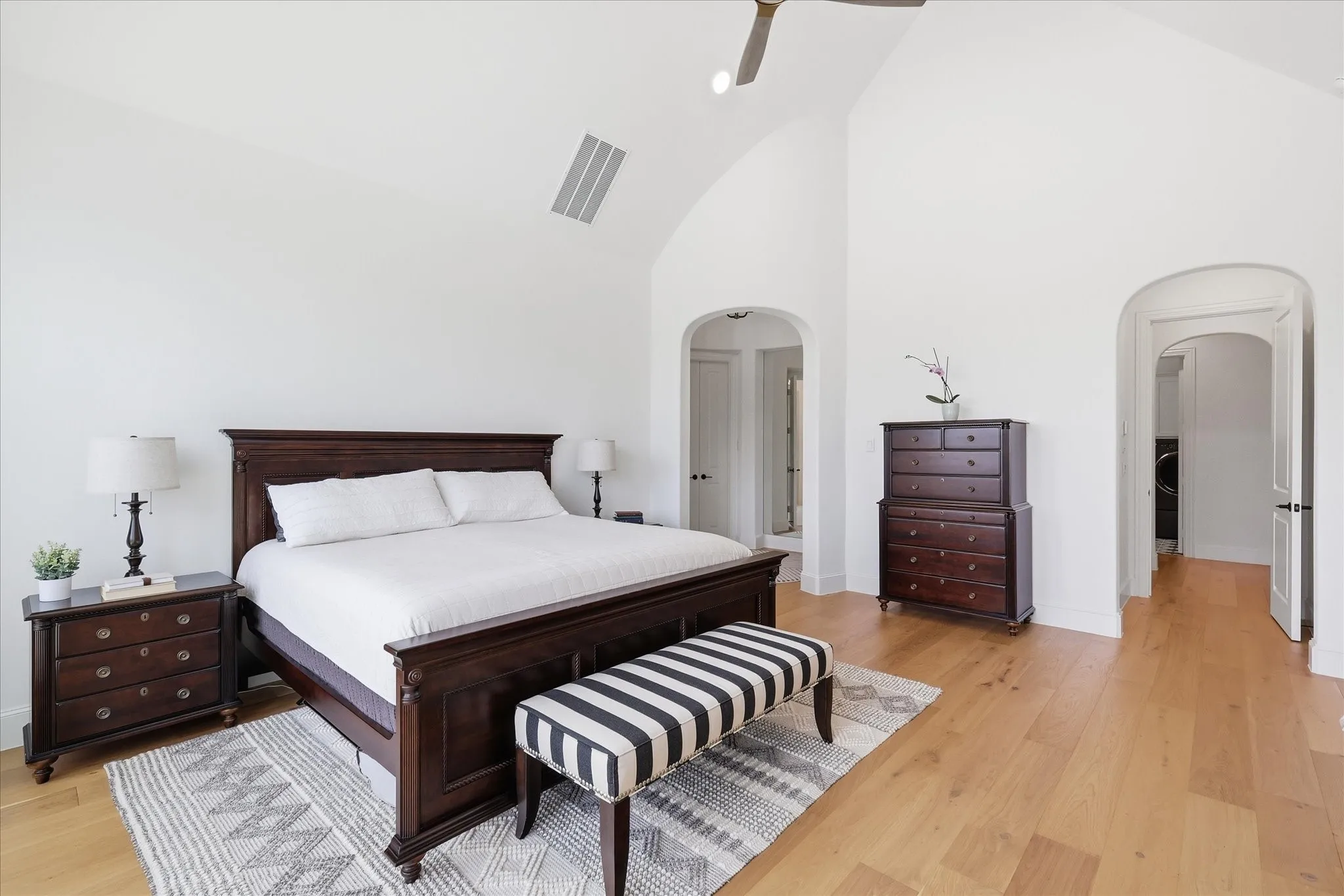 Spacious room featuring vaulted ceilings, wood-finish flooring, and white painted walls