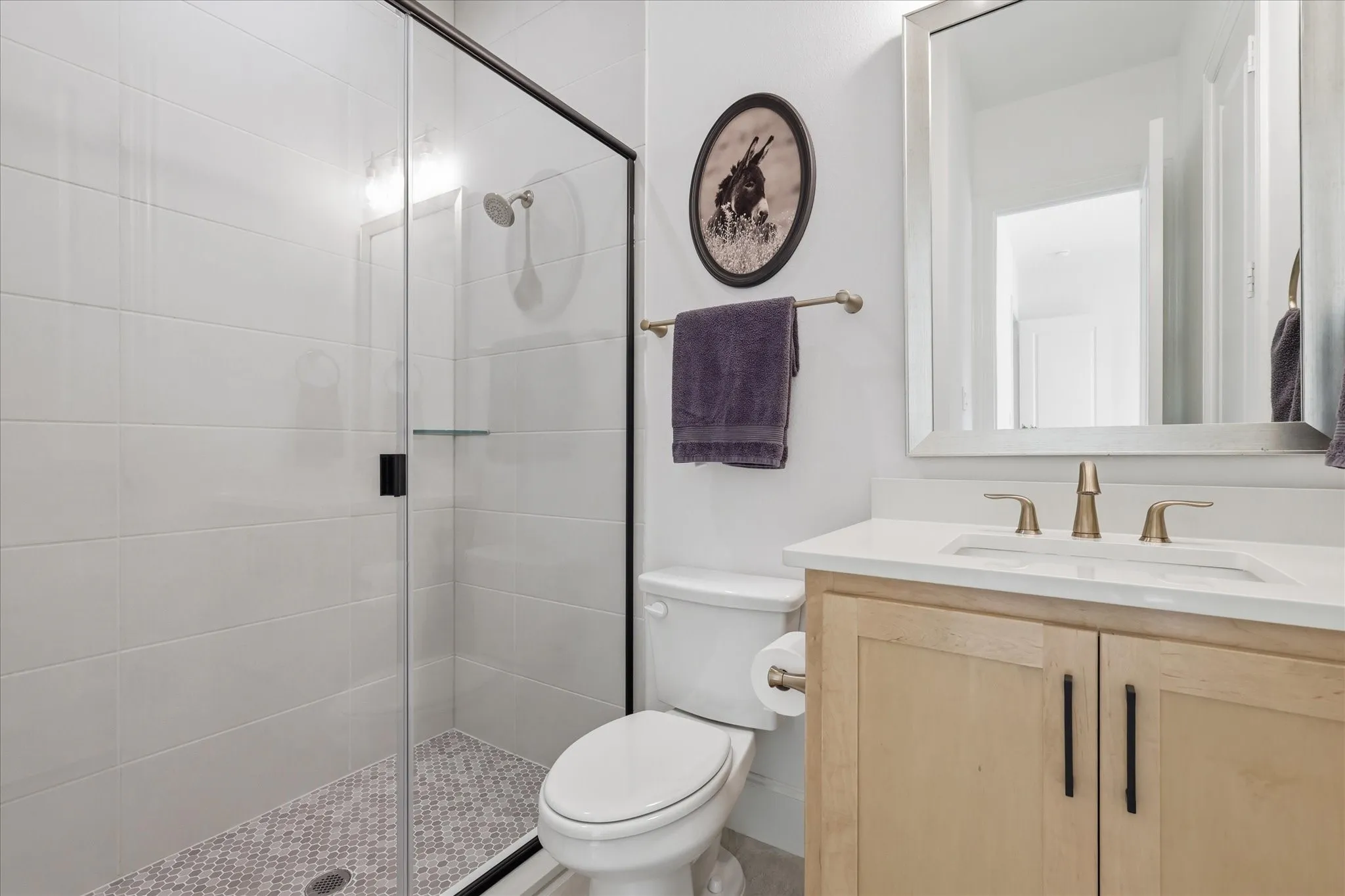 Modern bathroom featuring a walk-in shower with clear glass enclosure and black trim, white subway tile walls, and a mosaic tile shower floor