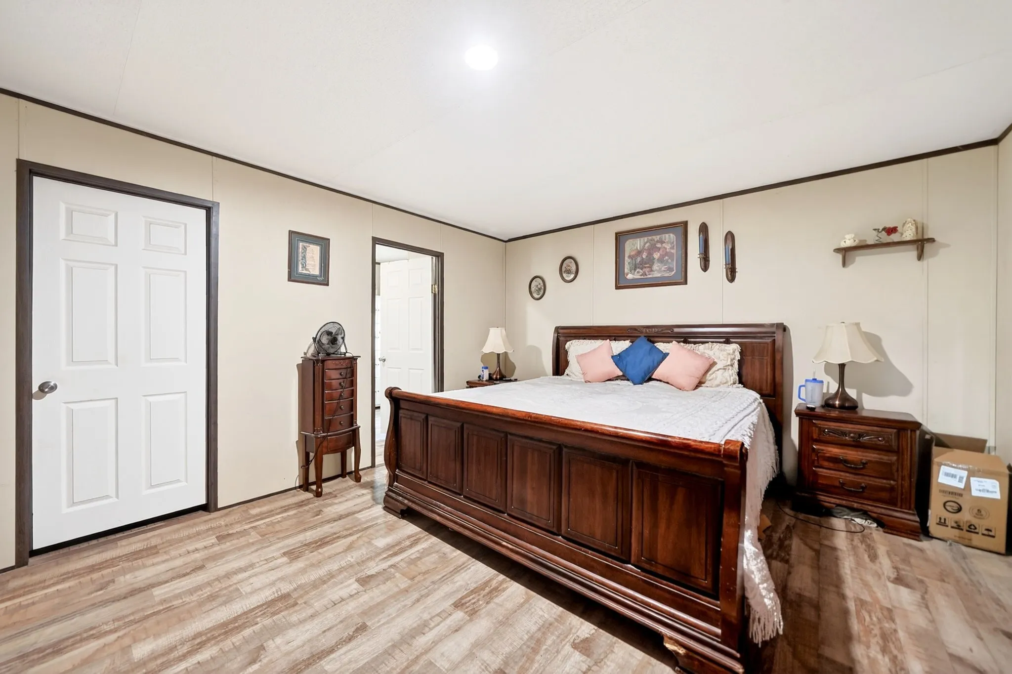 Interior room with wood-finish flooring, two white paneled doors with dark trim, and light-colored wall paneling