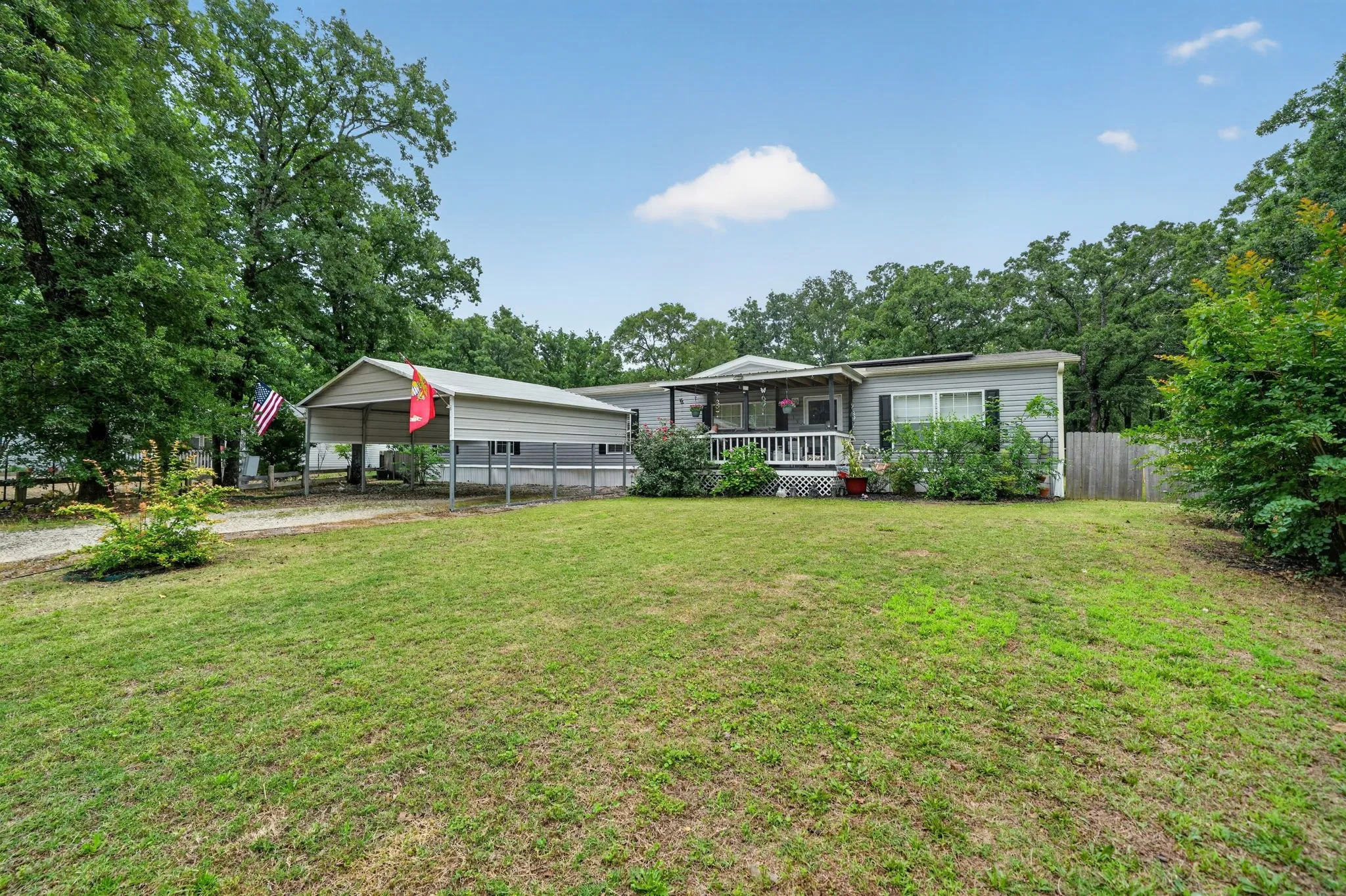 Single-story residence featuring light gray siding, dark shutters, and a covered front porch with white railing