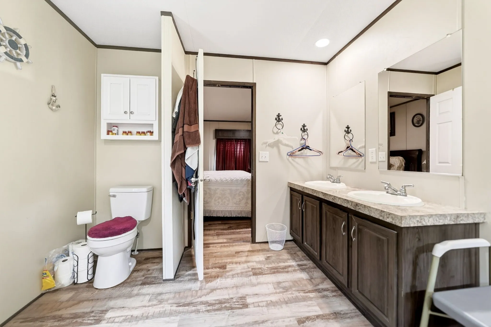 Bathroom featuring wood-finish flooring and a dual-sink vanity with dark wood cabinetry