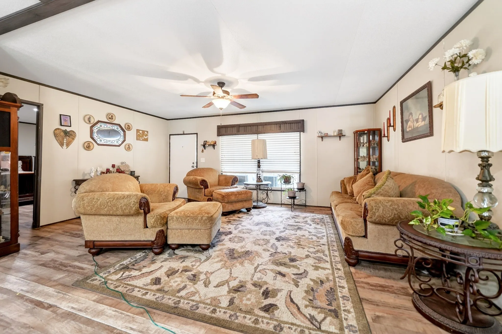 Spacious living area featuring wood-finish flooring, a ceiling fan, and window blinds