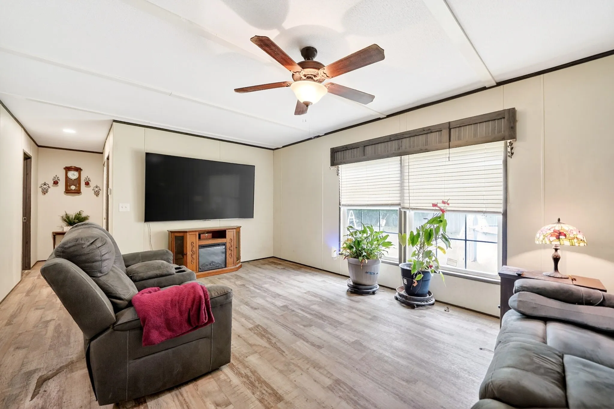 Light wood-finish flooring throughout, complemented by a ceiling fan with integrated lighting