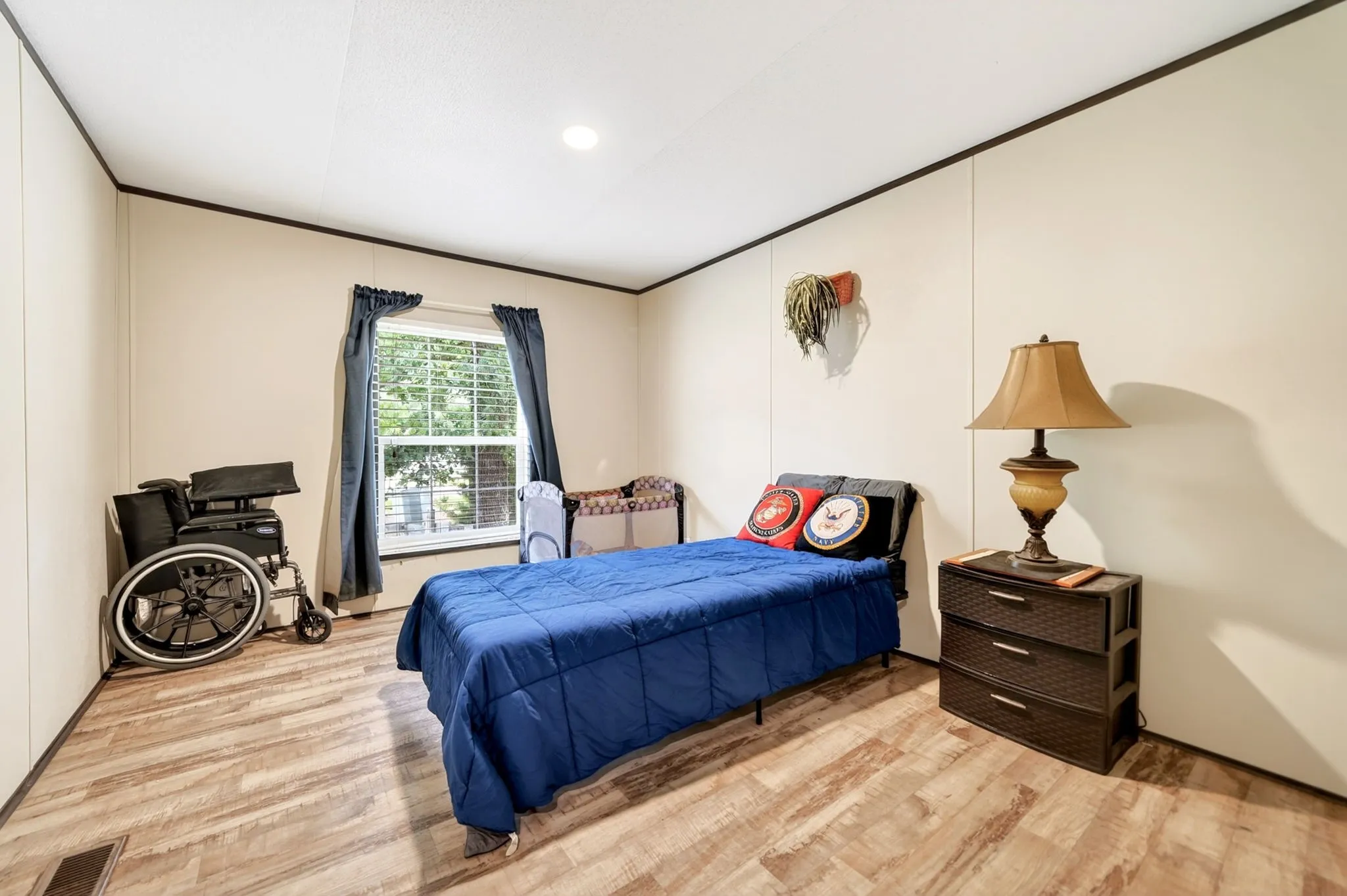 Bedroom featuring wood-finish flooring, a window with blinds and blue drapes, and recessed ceiling lighting