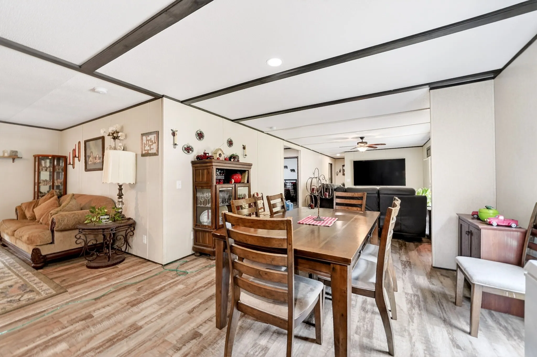 Open-concept living space featuring wood-finish flooring, a dining area with a wood table, and a living area with a ceiling fan