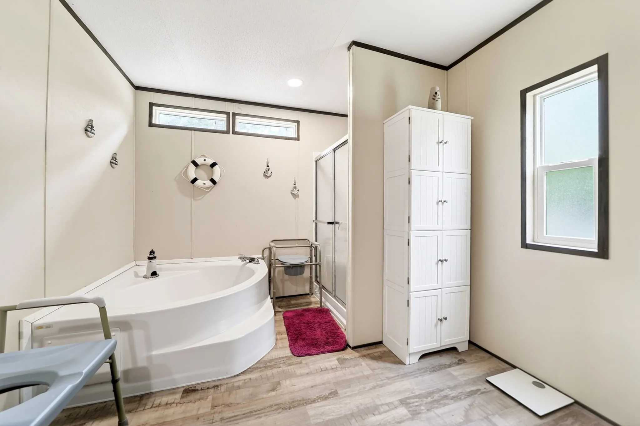 Bathroom featuring a corner soaking tub, a separate shower enclosure with a glass door, and wood-finish flooring