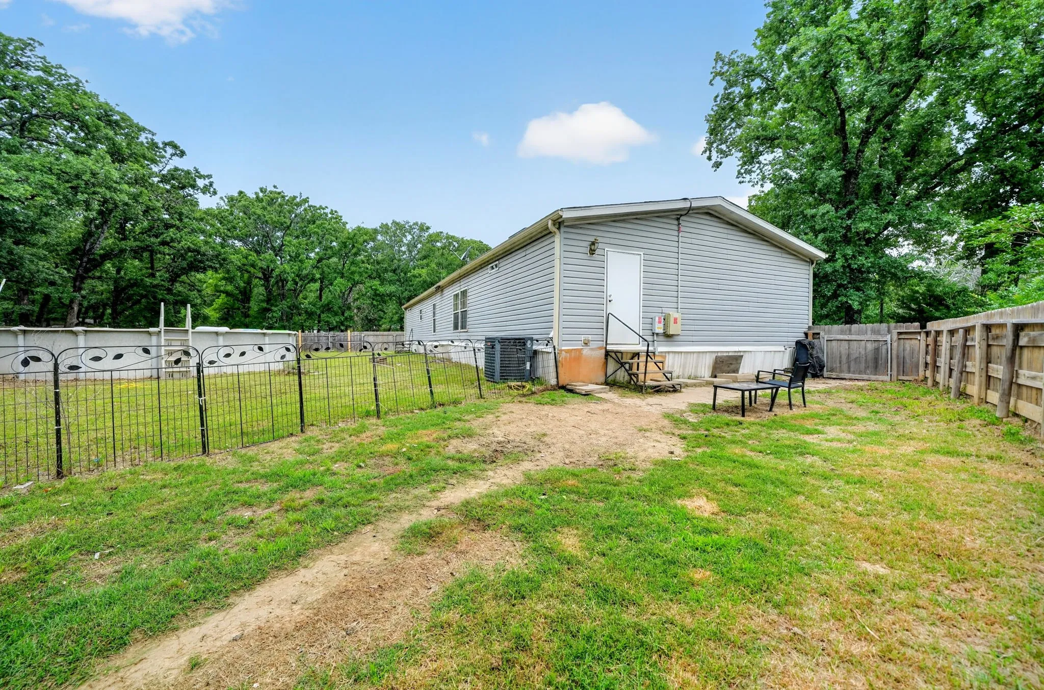 Expansive rear yard featuring partial wood fencing and a separate black metal fence enclosure