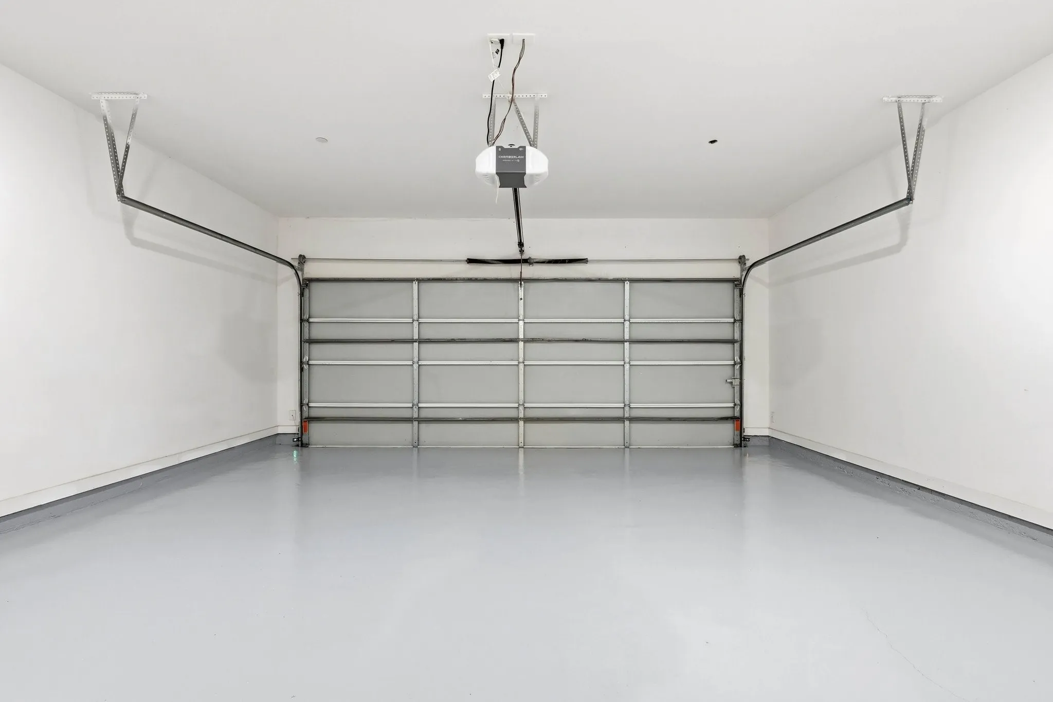 Spacious garage featuring a light gray epoxy floor coating, crisp white walls, and an automatic garage door opener system