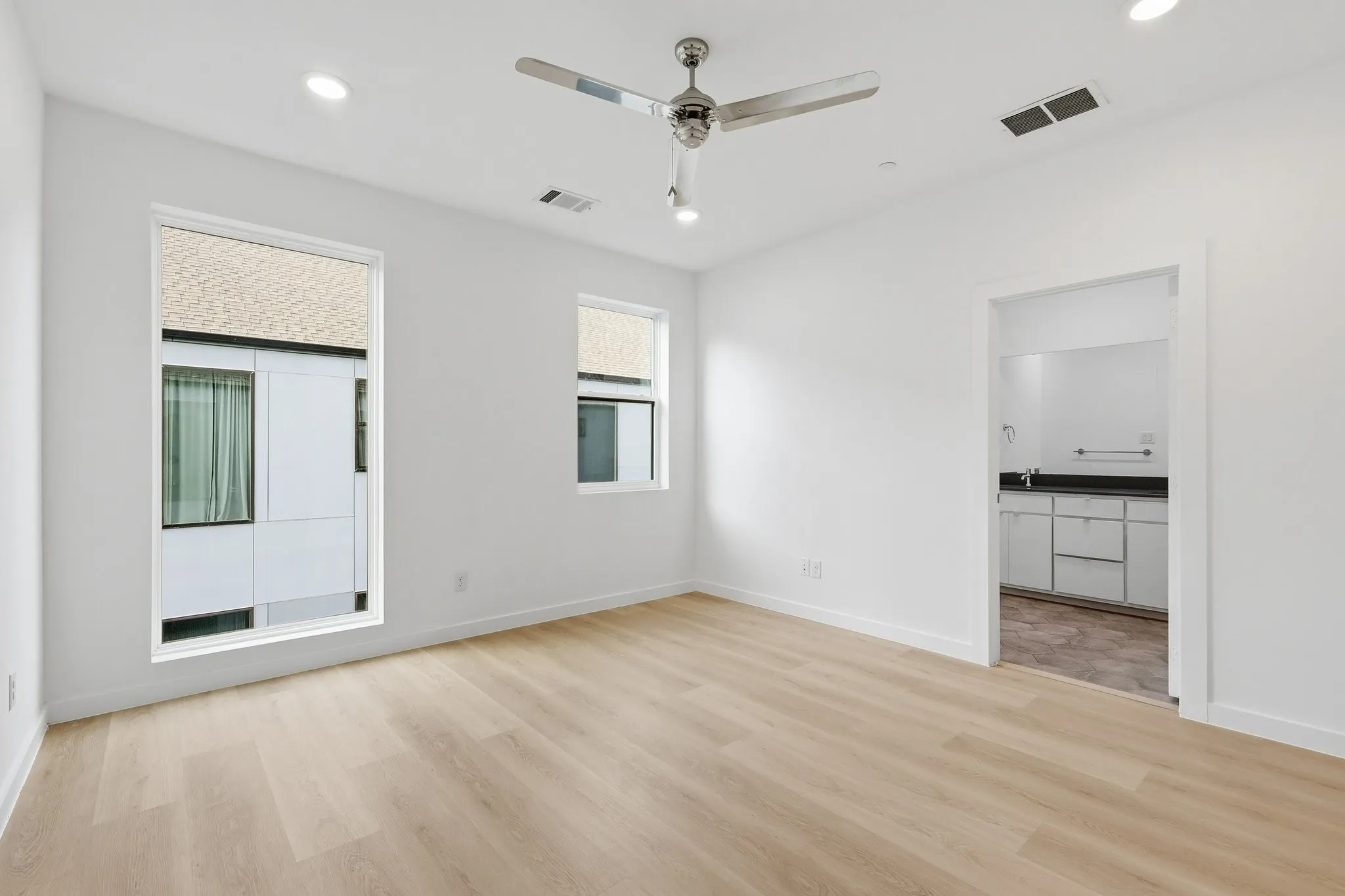 Bright room featuring light wood-finish flooring, recessed lighting, and a ceiling fan