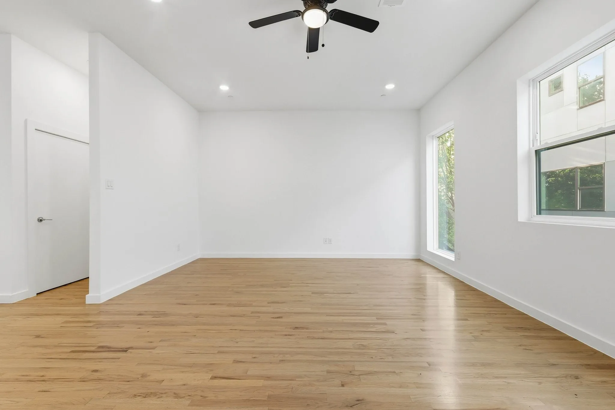 Spacious room featuring wood-finish flooring, recessed lighting, and a ceiling fan