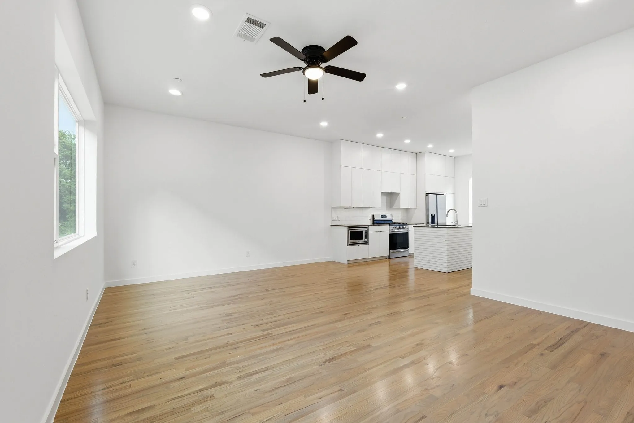 Open-concept living space featuring wood-finish flooring, recessed lighting, and a contemporary ceiling fan