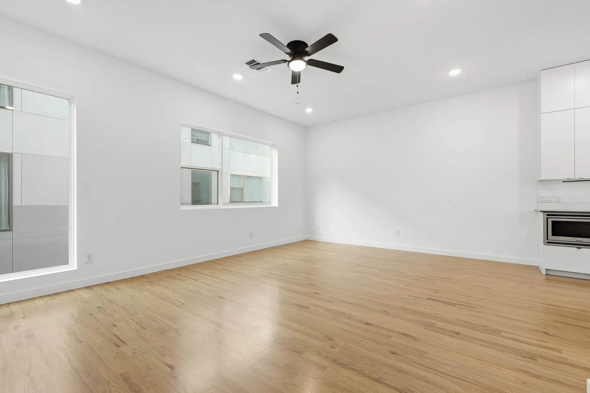 Open-concept living space with light wood-finish flooring, recessed lighting, and a contemporary ceiling fan