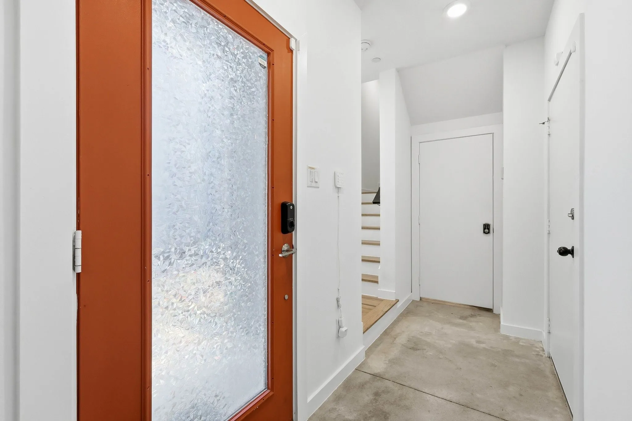 Entryway featuring a terracotta-hued door with textured privacy glass and a smart lock system