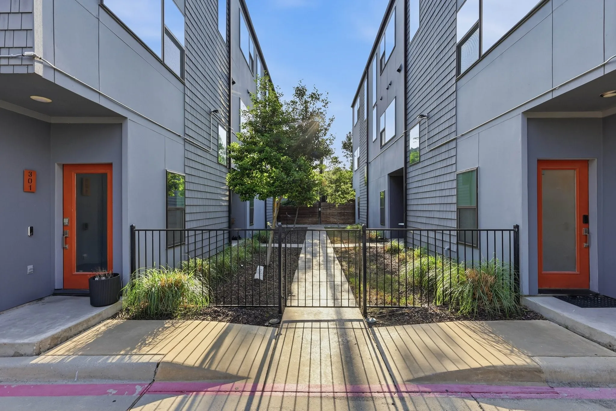 Contemporary exterior featuring gray siding, orange entry doors, and multi-pane windows