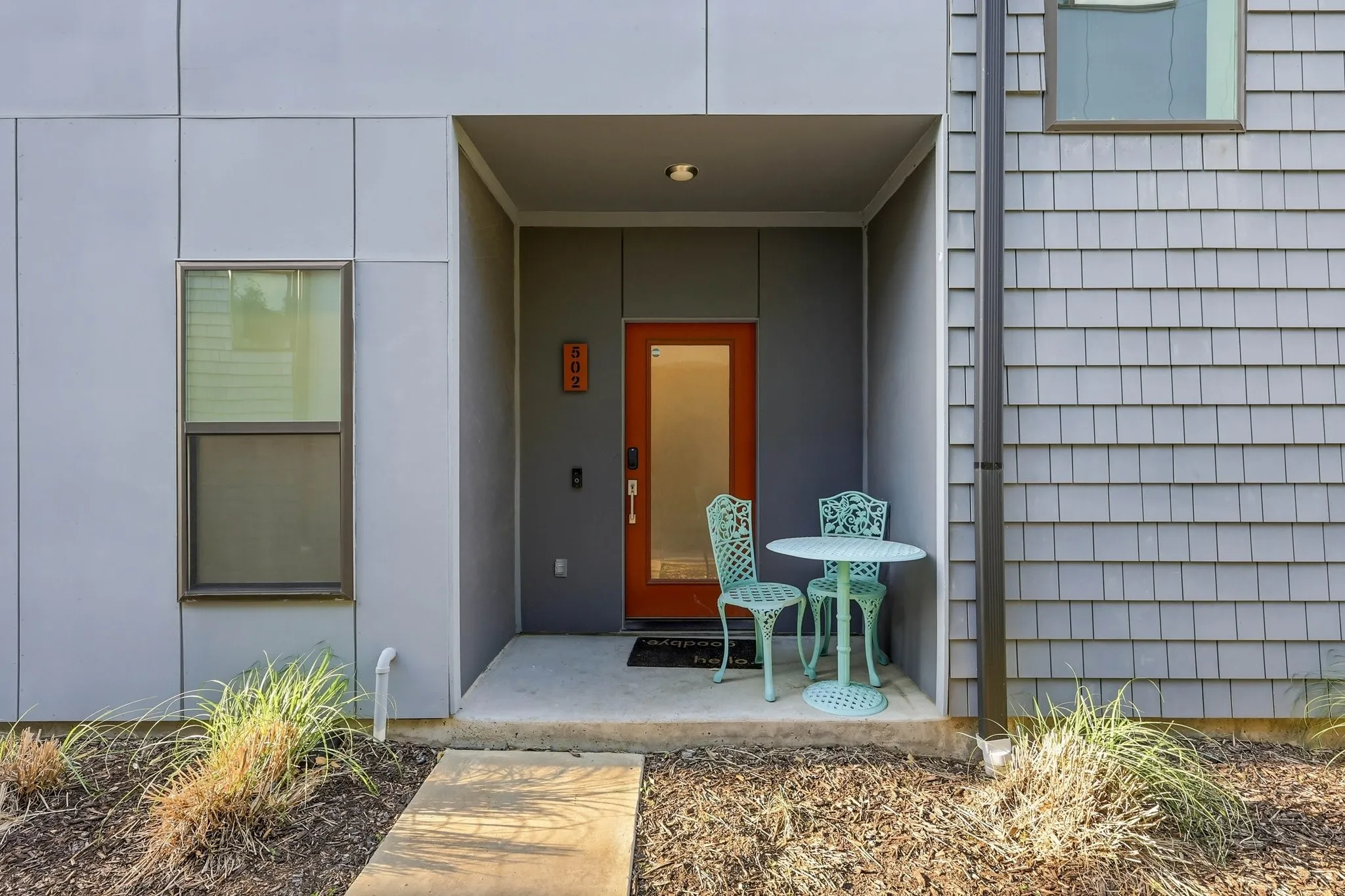 Contemporary exterior featuring a covered entry, vertical panel siding, and horizontal shingle siding