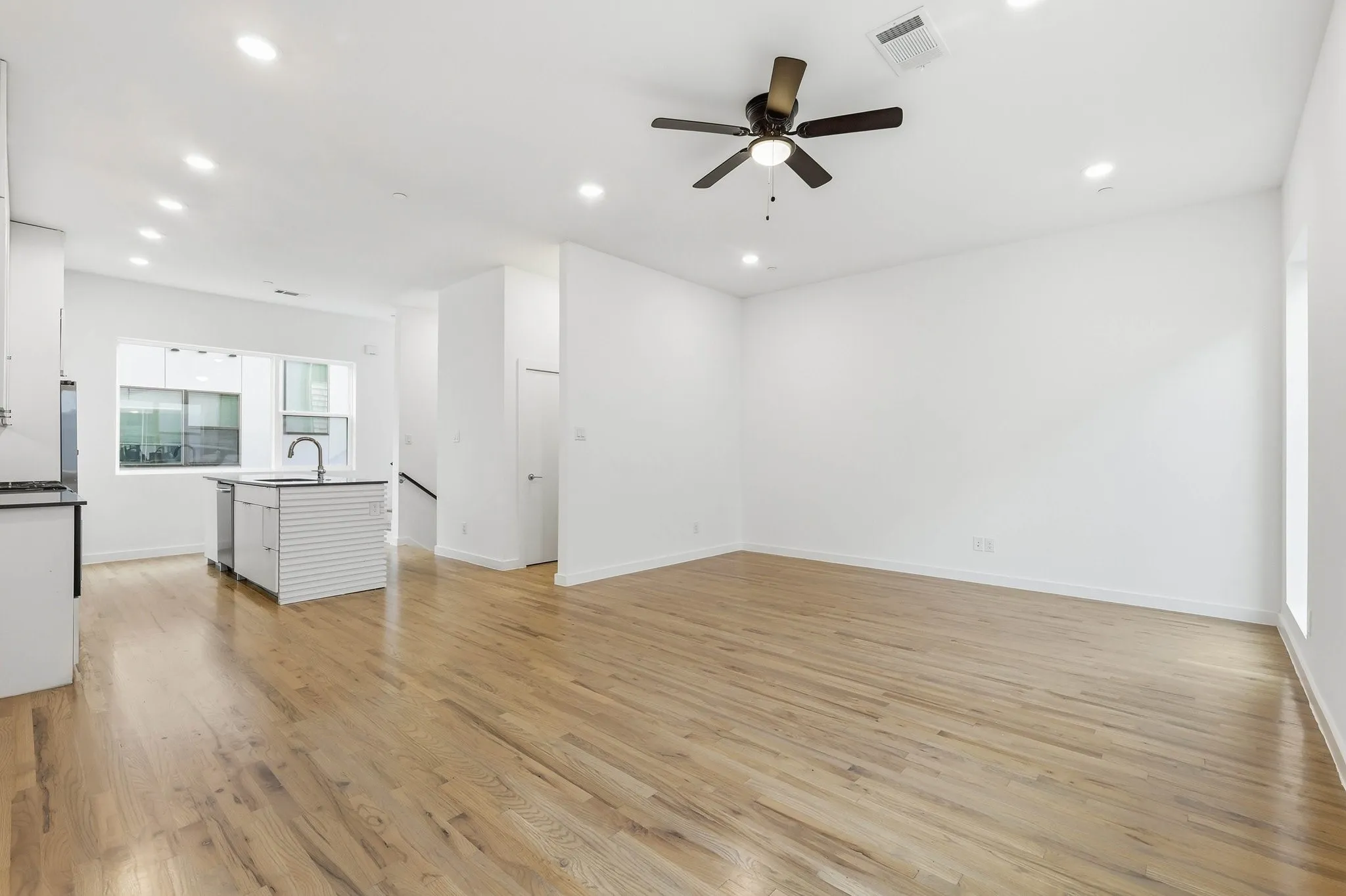 Open-concept living area featuring light wood-finish flooring, recessed lighting, and a ceiling fan