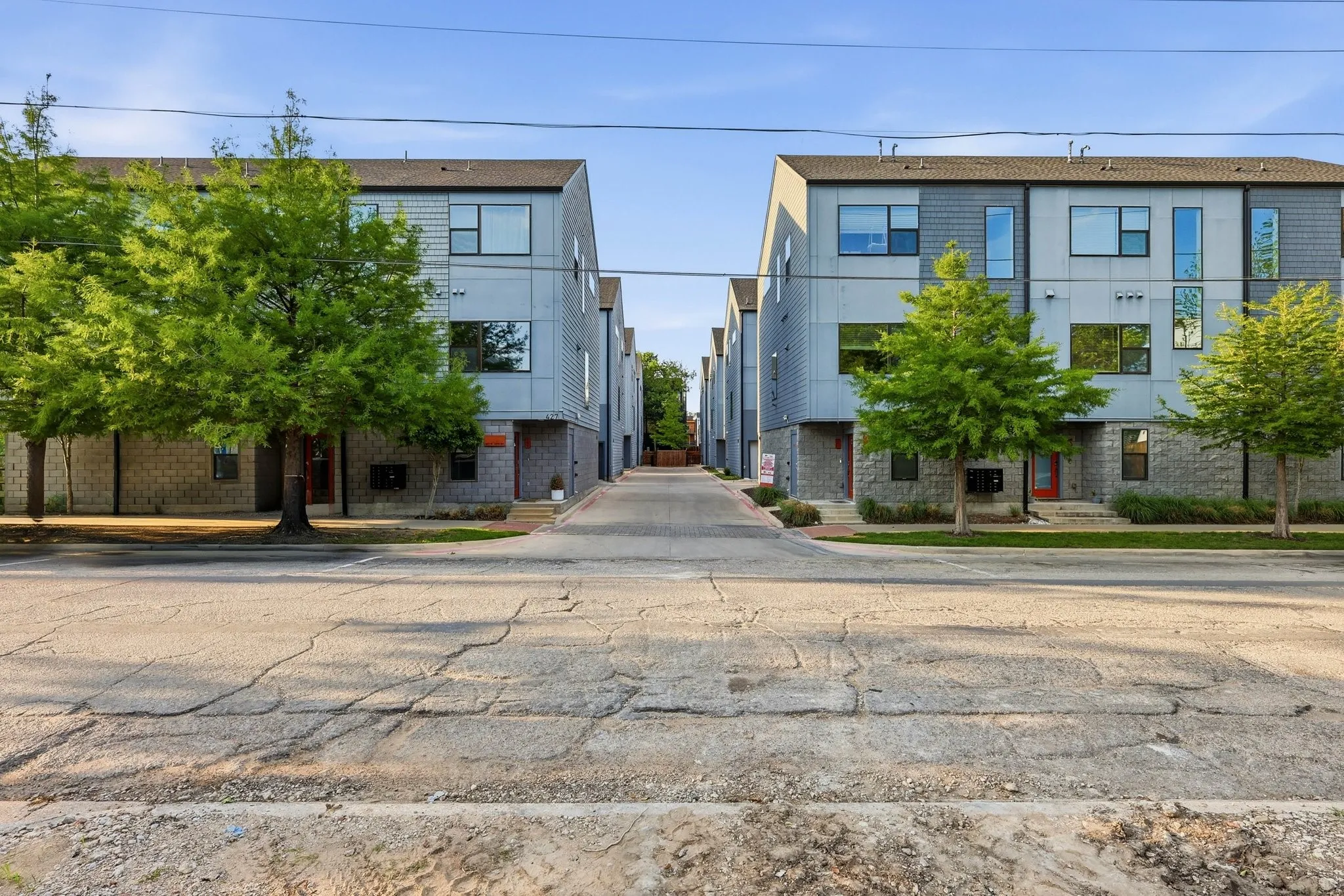 Contemporary townhome-style residences featuring multi-story facades, extensive window placements, and mature trees providing natural shading