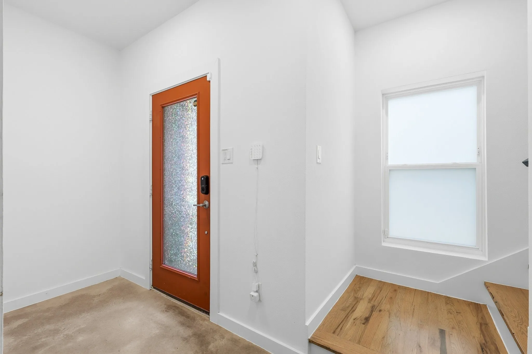 Entryway featuring a wood-panel door with frosted glass insert, white baseboards, and a window with frosted glass