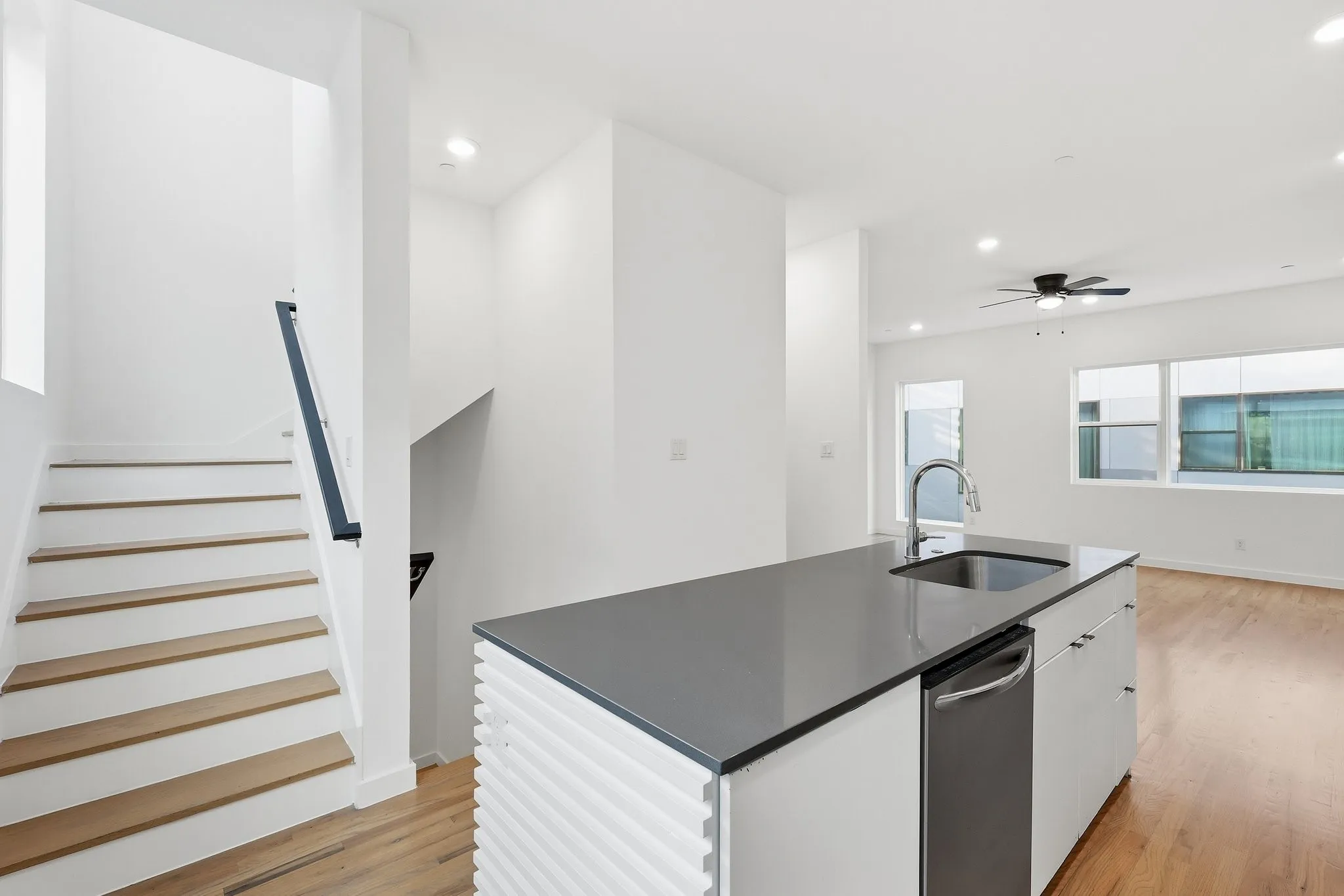 Kitchen island featuring a single-basin sink with a gooseneck faucet, integrated dishwasher, and dark countertop