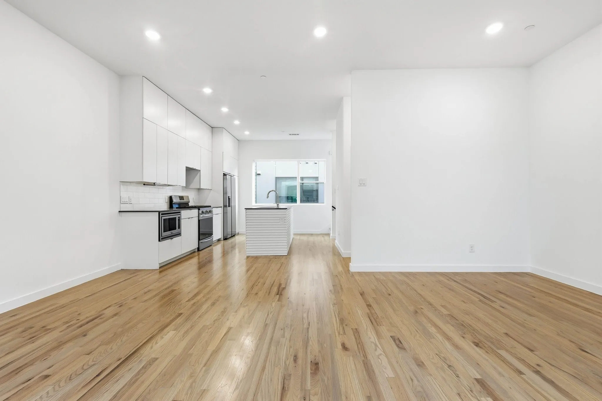 Open-concept living space featuring wood-finish flooring, recessed lighting, and a modern kitchen