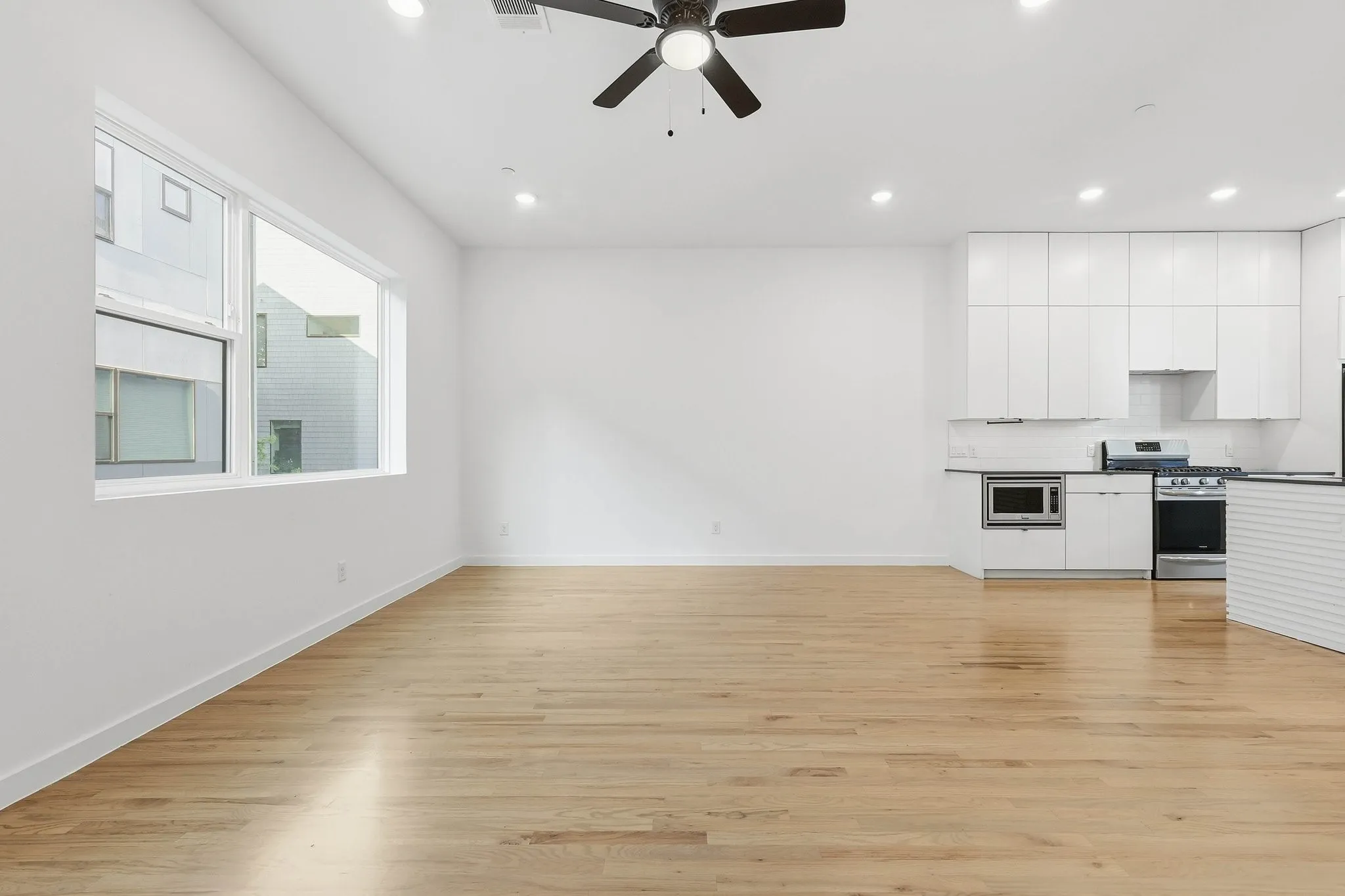Open-concept living space featuring wood-finish flooring, recessed lighting, and a ceiling fan