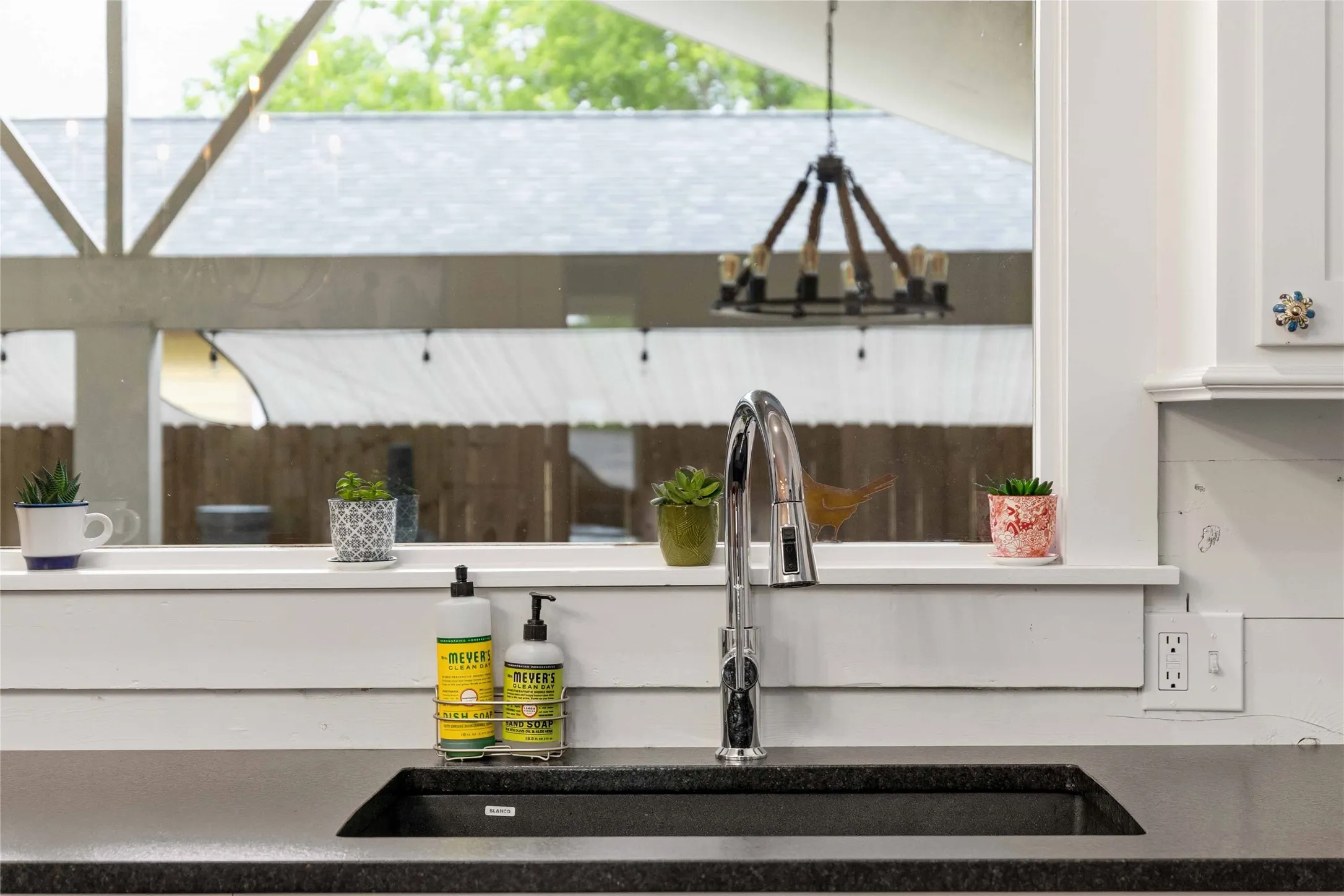 Kitchen sink featuring a chrome high-arc faucet, an undermount black sink, and a dark countertop