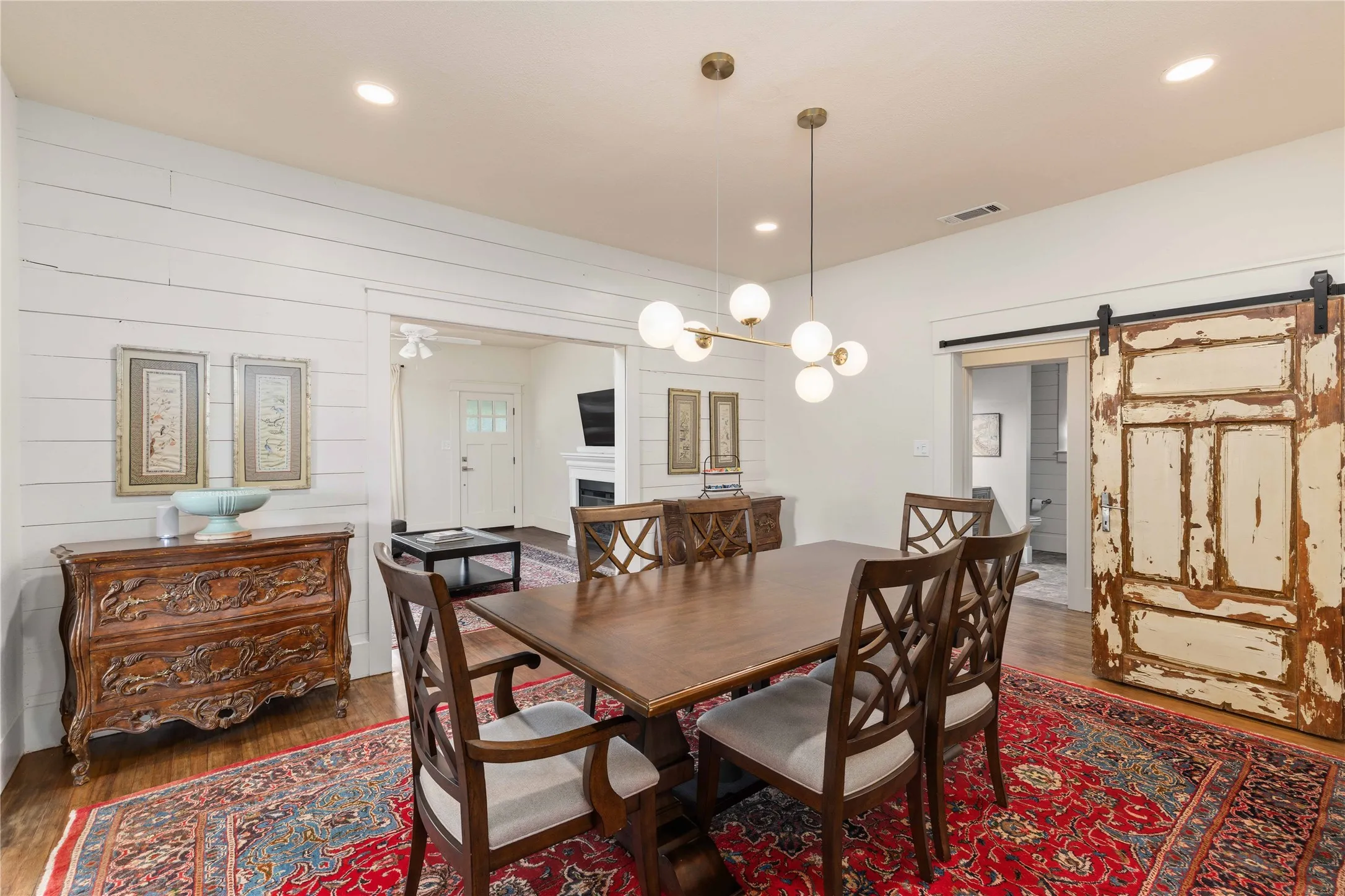 Dining area featuring hardwood flooring, shiplap accent wall, recessed lighting, and a modern chandelier