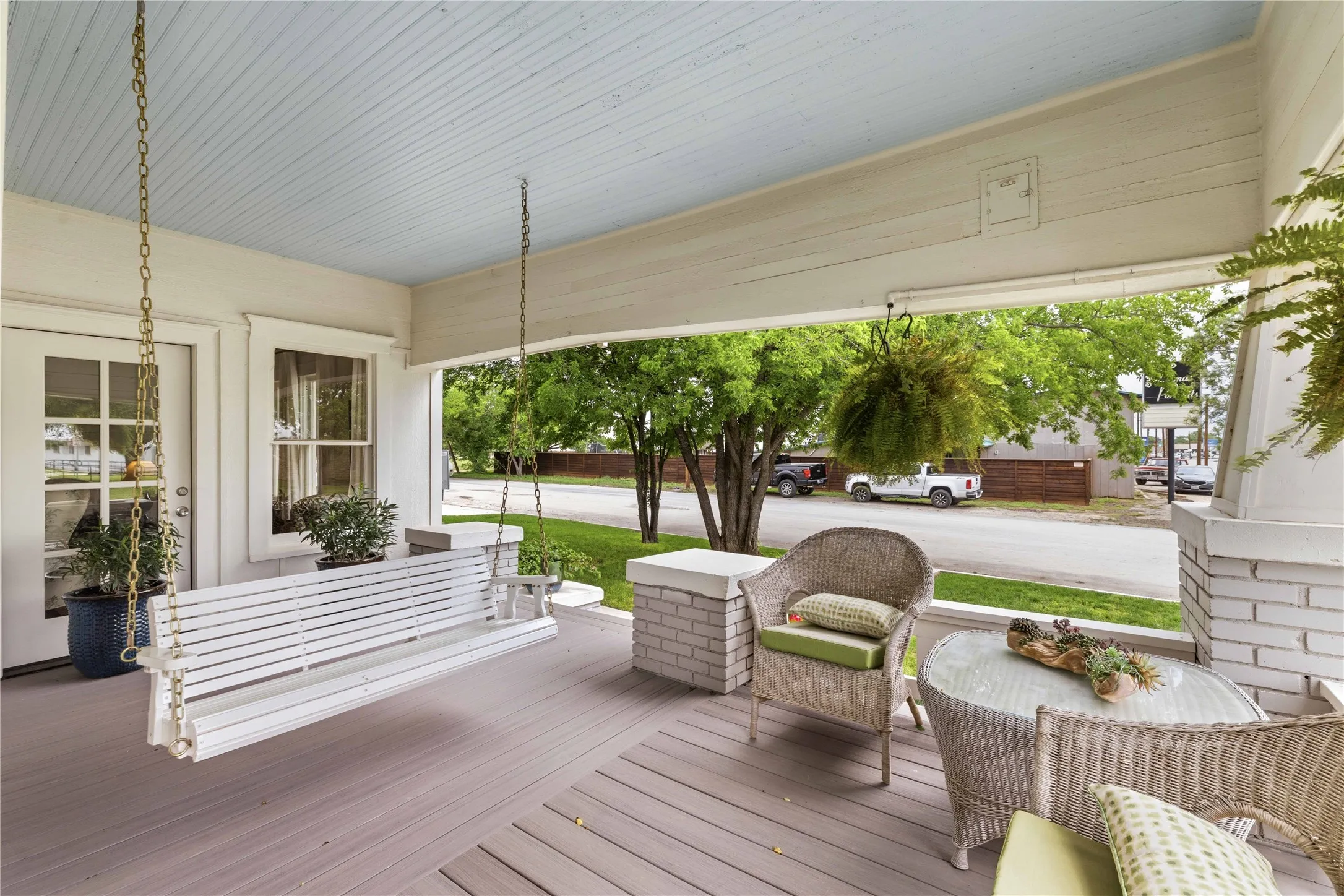 Covered front porch featuring a porch swing, beadboard ceiling, and painted wood flooring