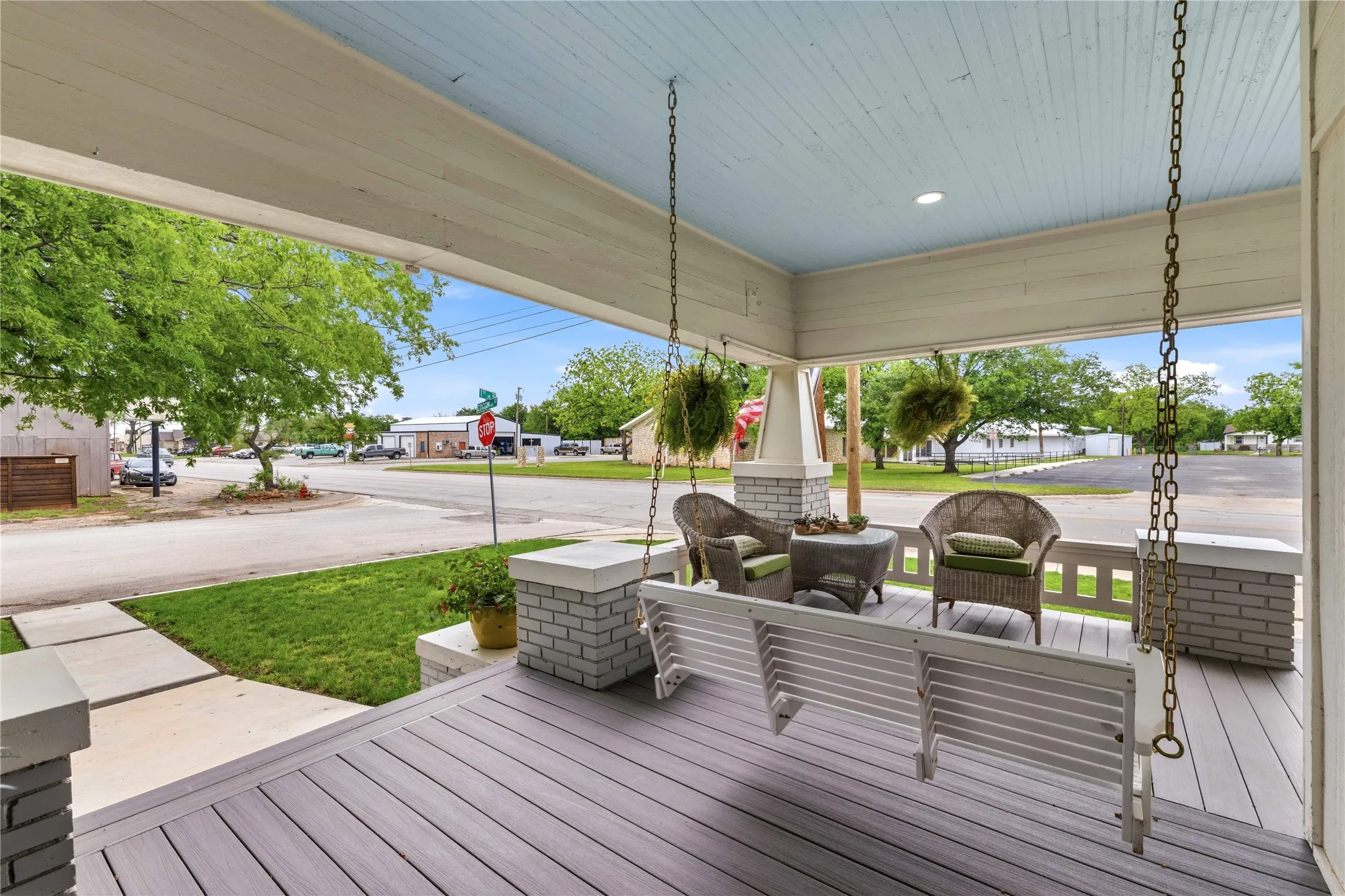Expansive covered front porch featuring a porch swing, planked ceiling with recessed lighting, and composite decking