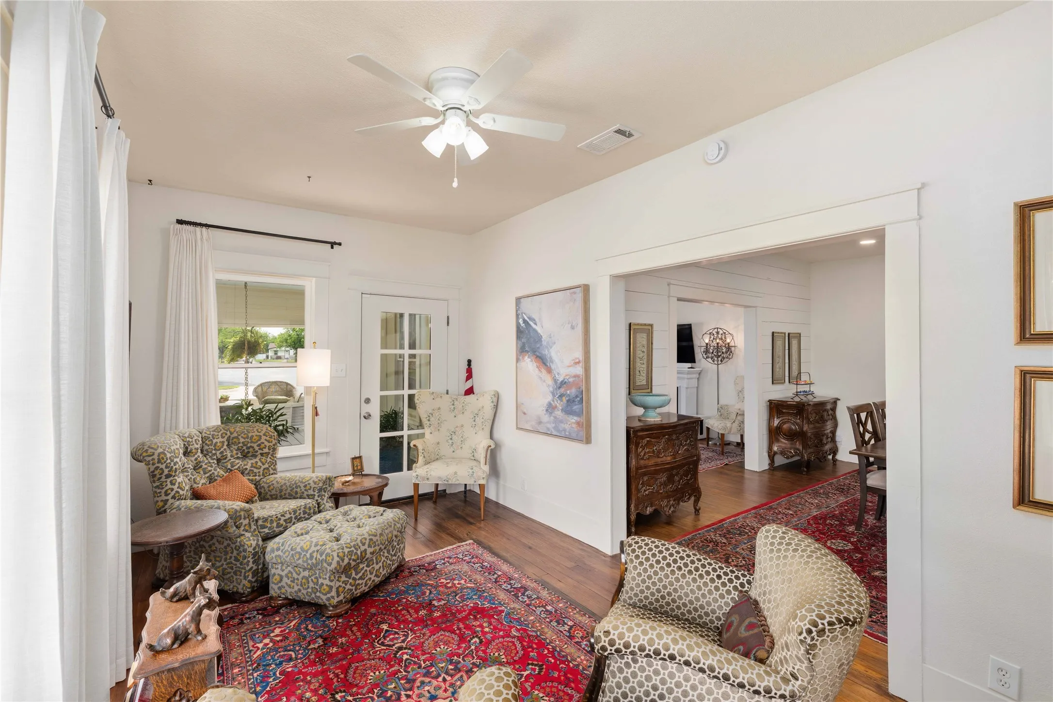 Bright living space featuring wood-finish flooring, a ceiling fan, and white trim throughout