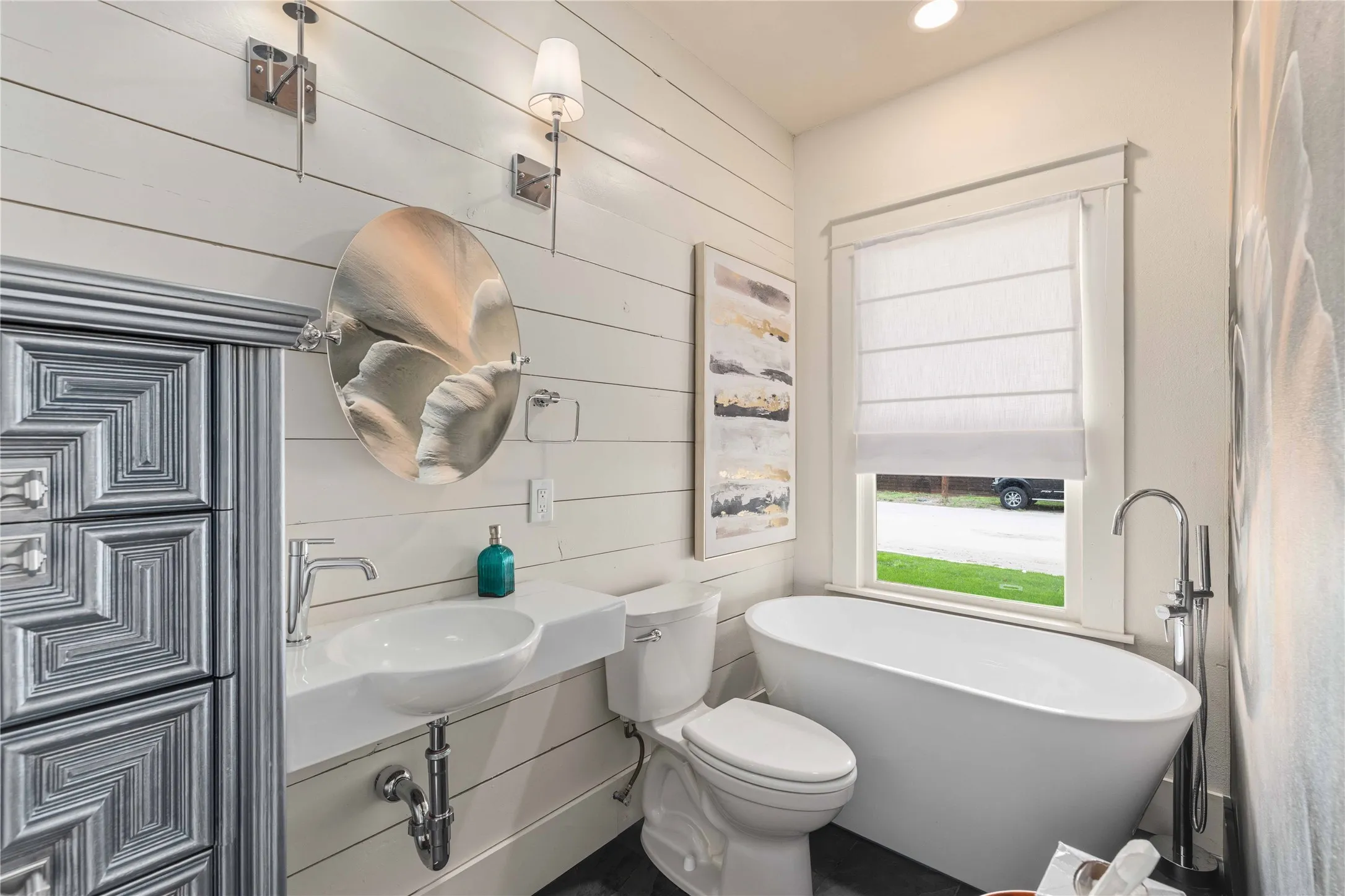 Bathroom featuring white shiplap walls, a freestanding soaking tub, a vessel sink with a wall-mounted countertop, and chrome fixtures