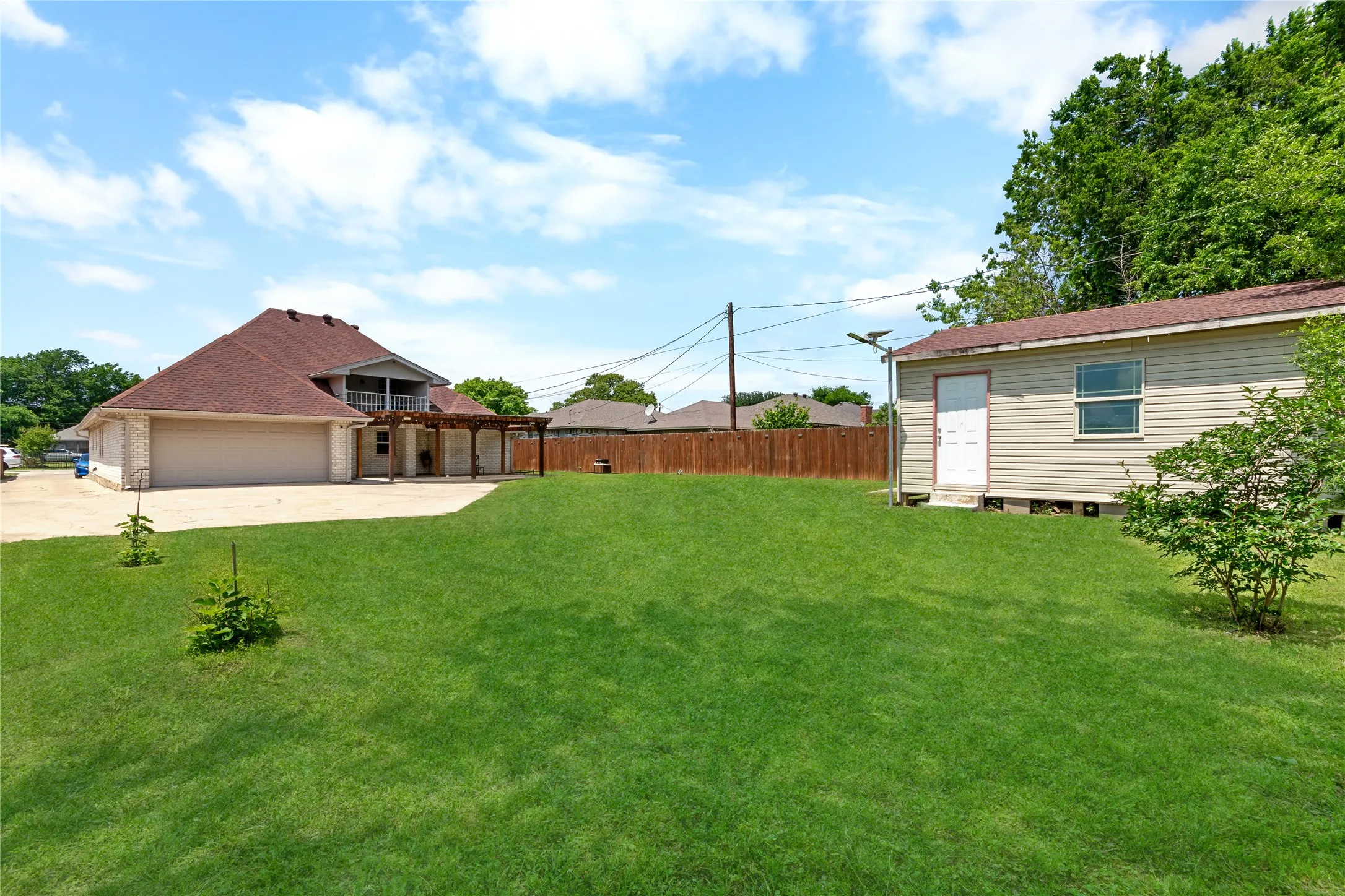Expansive green lawn with a detached storage building and wood privacy fencing