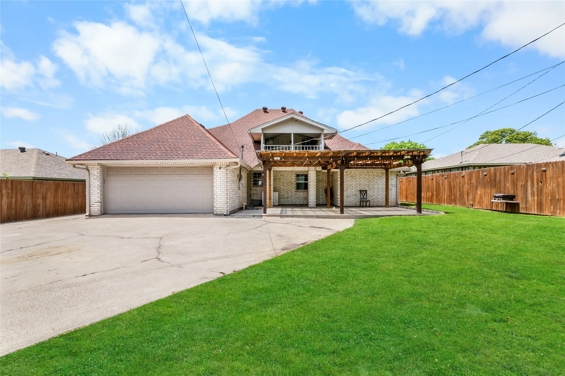 Expansive backyard featuring a lush lawn, a large concrete patio, and a wood pergola