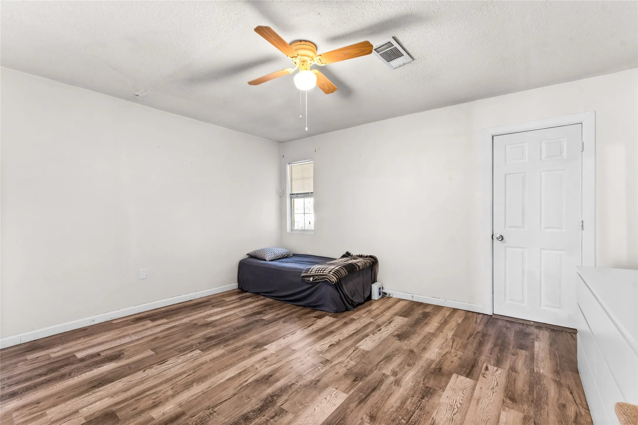 Upstairs bedroom featuring wood-finish flooring, white walls, and a multi-pane window