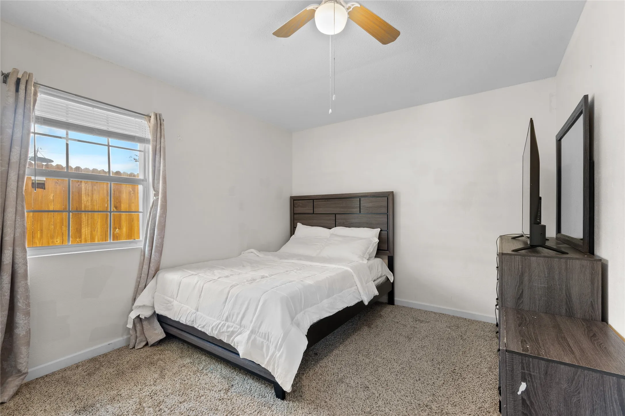 Neutral wall tones create a bright ambiance in this room, complemented by a ceiling fan