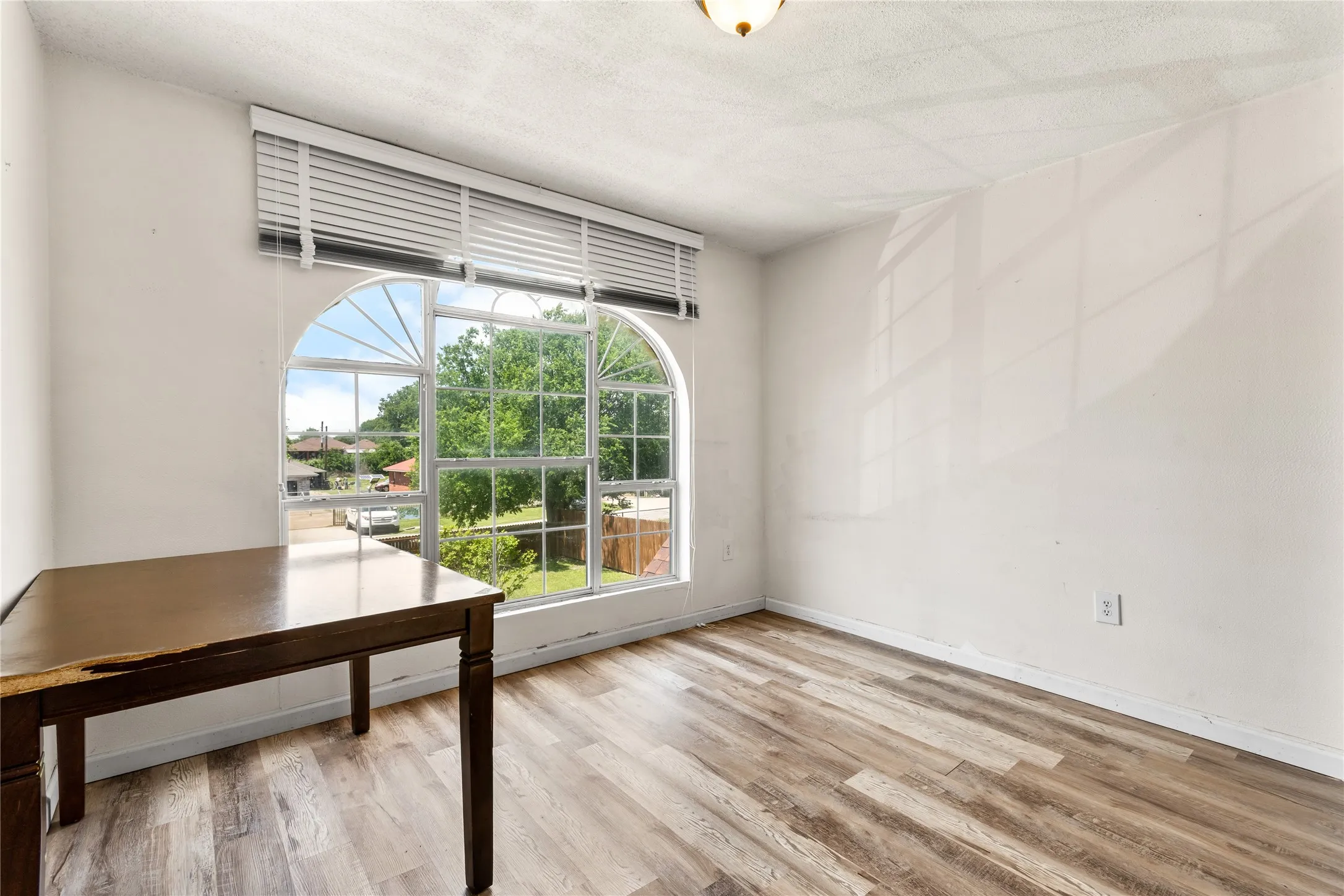 Bright office or flex room featuring a large arched window with horizontal blinds