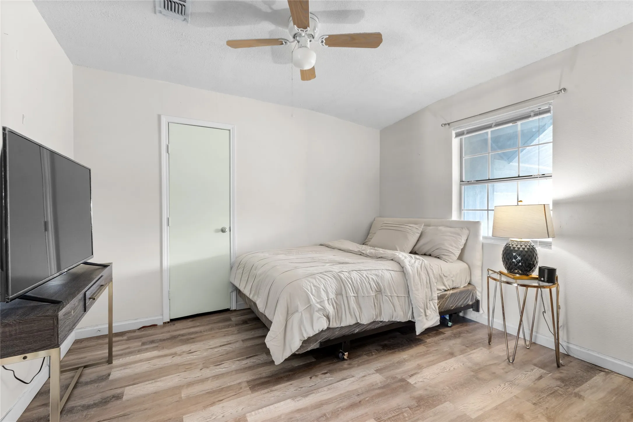 Bedroom featuring wood-finish flooring, a window with horizontal blinds, and a ceiling fan with light fixture