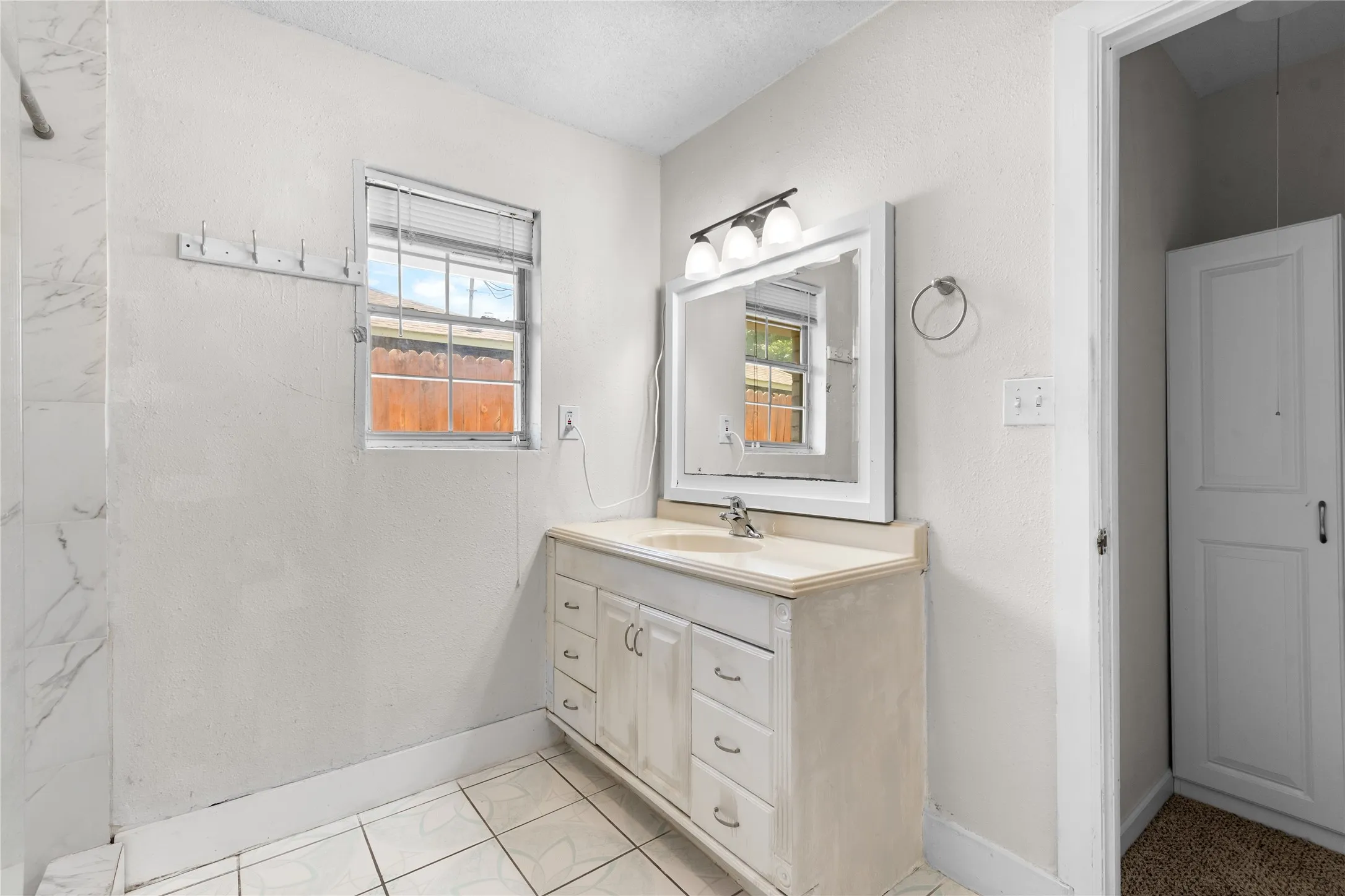 Bathroom featuring a single vanity with storage, a rectangular mirror, and overhead lighting