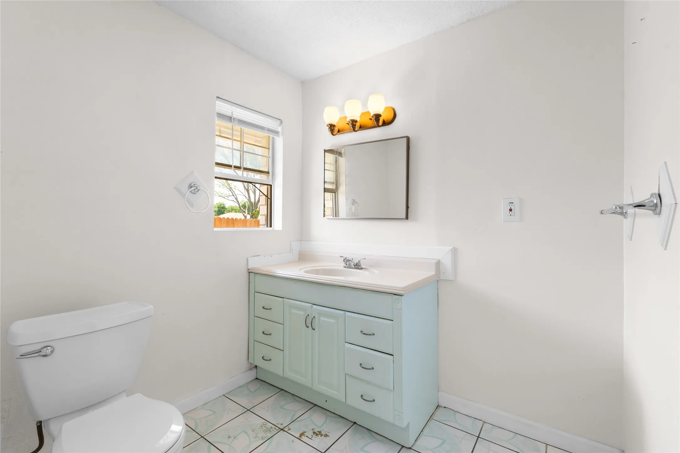 Bathroom with a light blue vanity, integrated sink, and a framed mirror