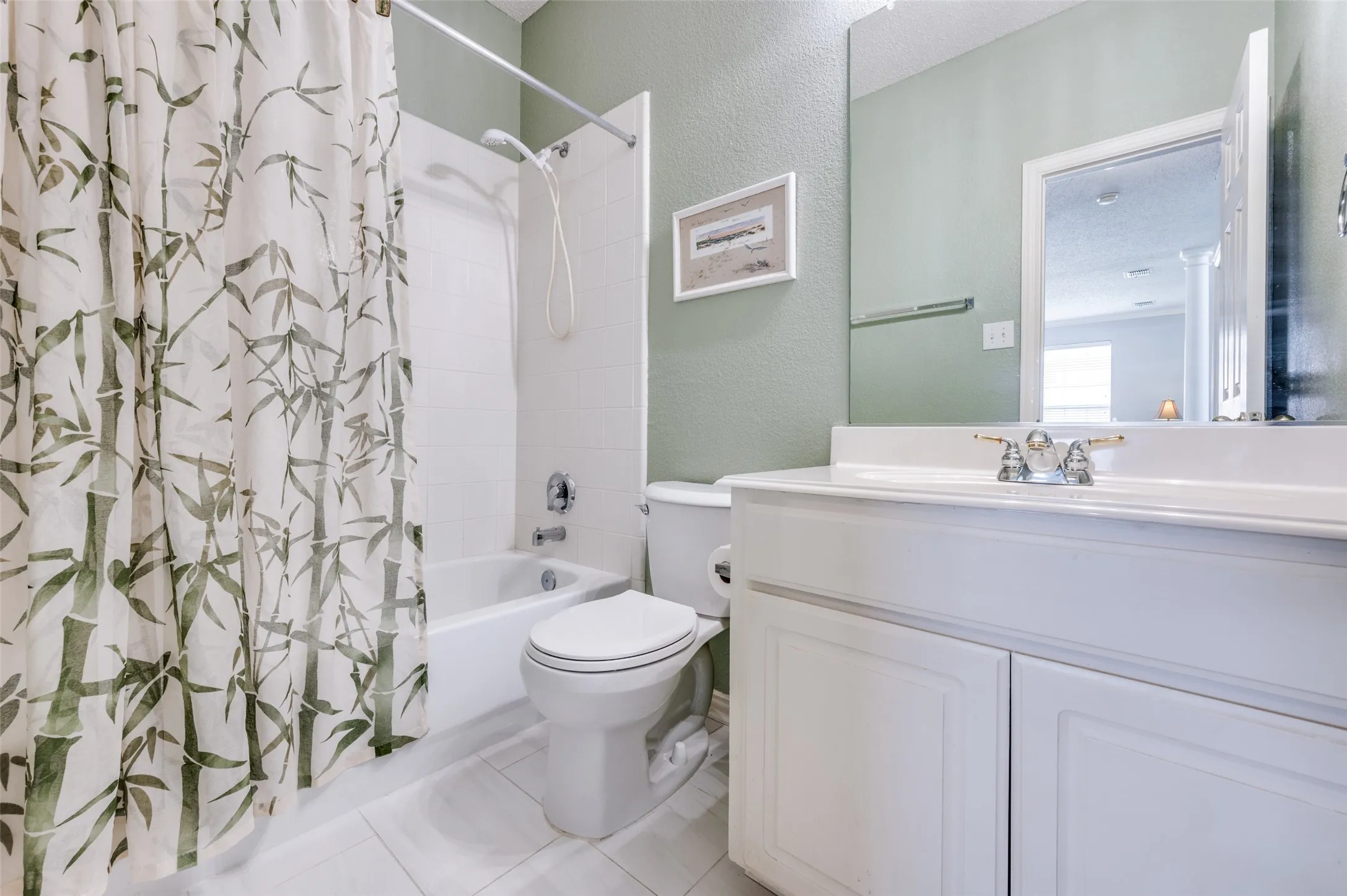 Bathroom featuring a white vanity with integrated sink, chrome fixtures, a full-width mirror, and a white tiled shower-tub combination